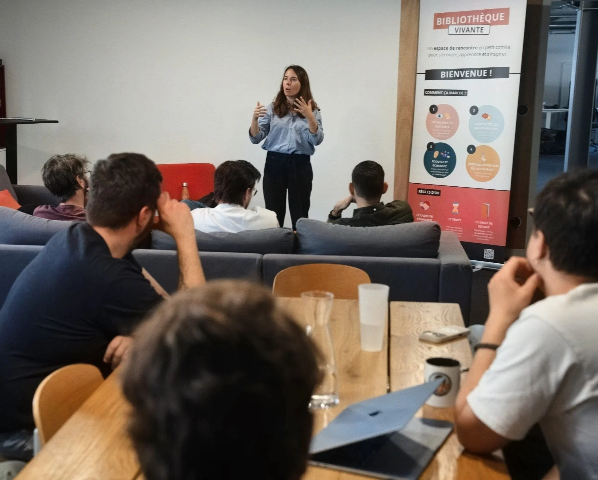 Une femme donne une présentation devant un groupe d'étudiants dans une salle de classe ou un espace de réunion.