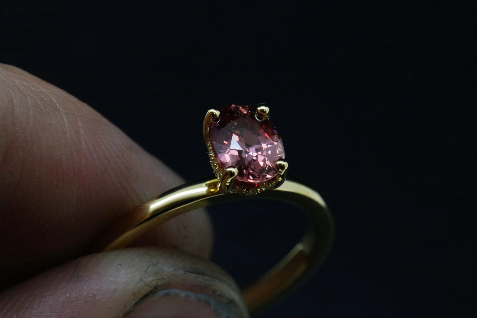 A gold ring with an oval pink gemstone in a prong setting.