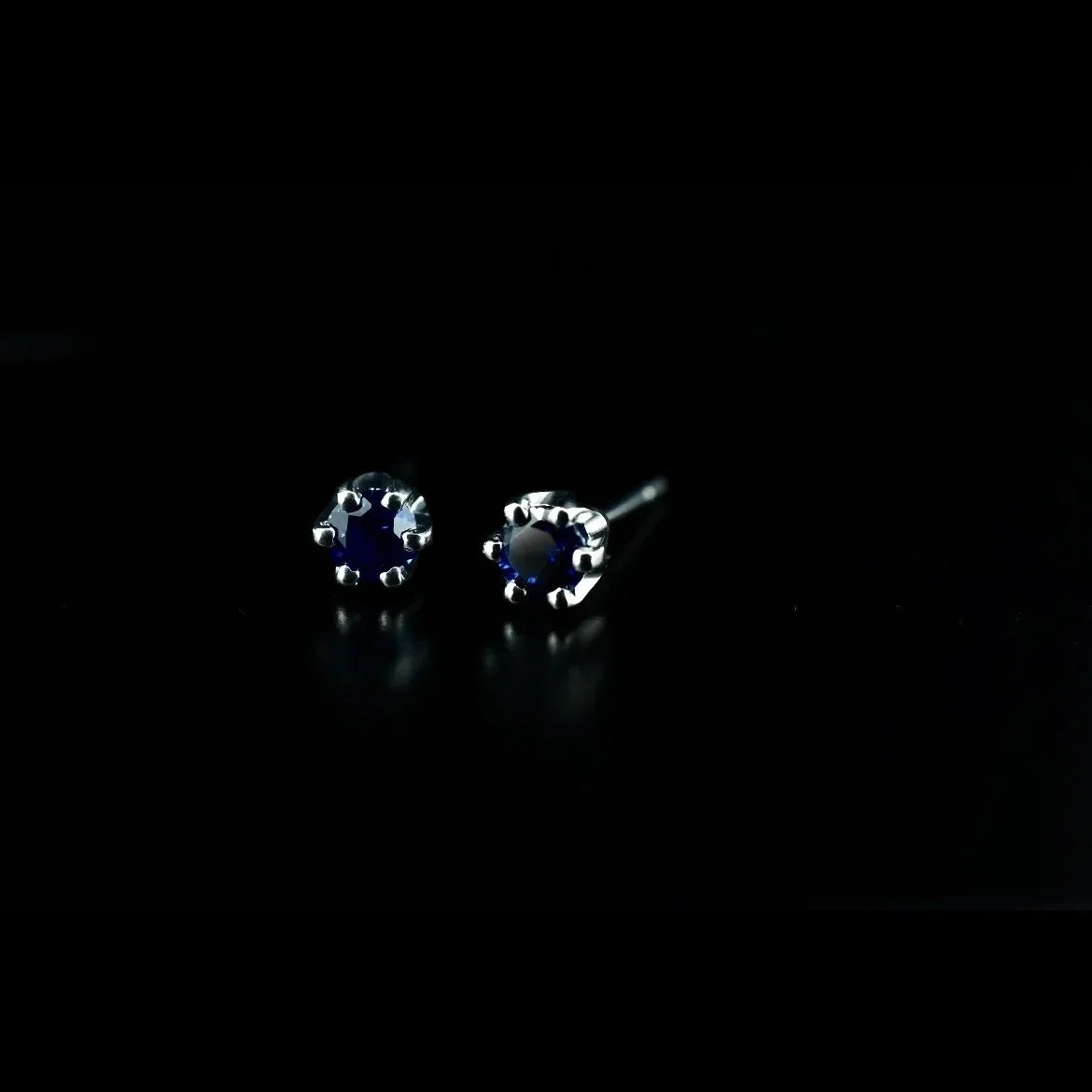 Silver earrings with dark blue gemstones on a black background.