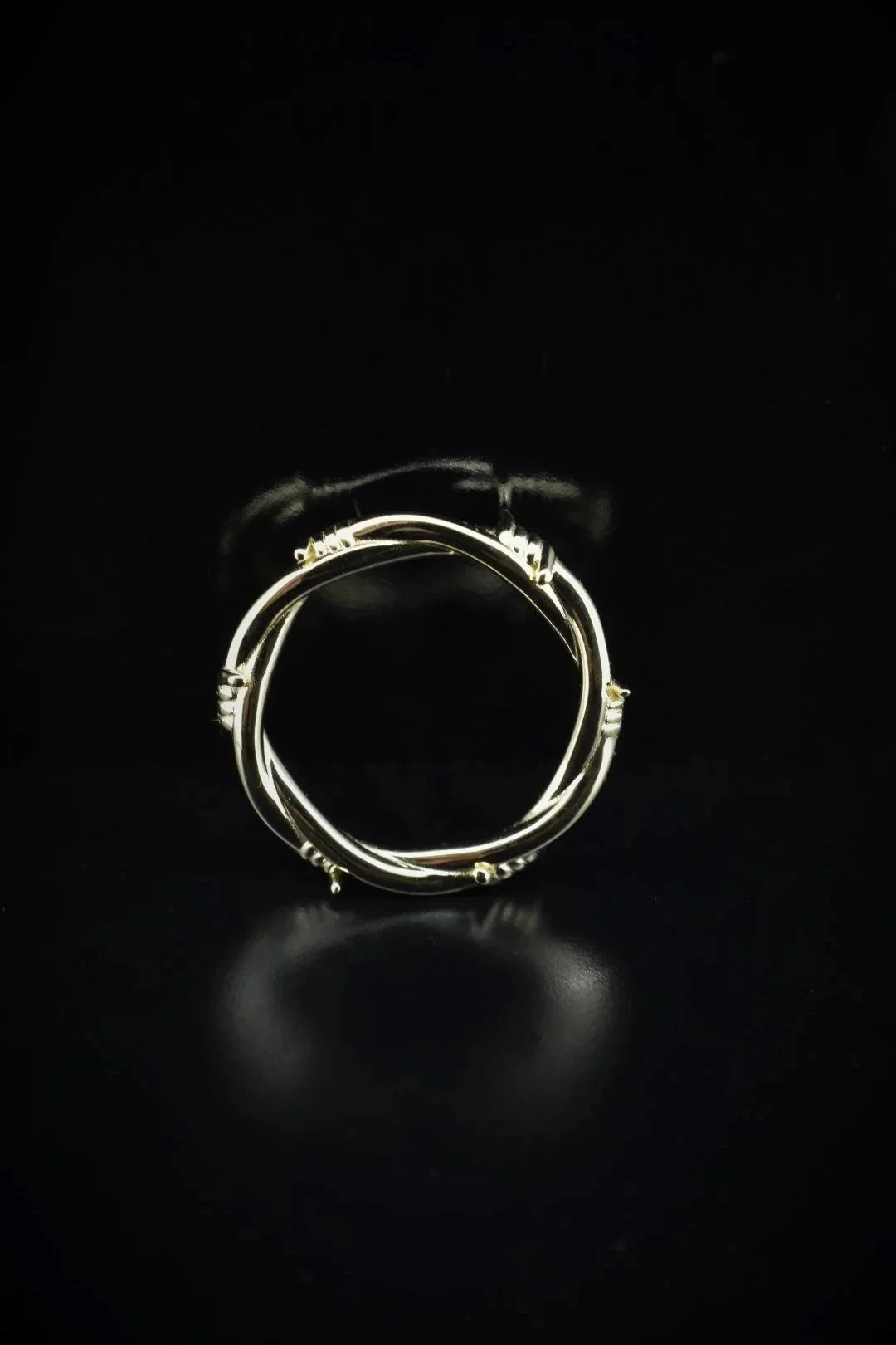Three intertwined silver rings with a reflective surface on a black background.