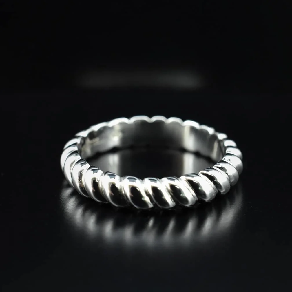 A silver ring with a twisted rope design on a black background.