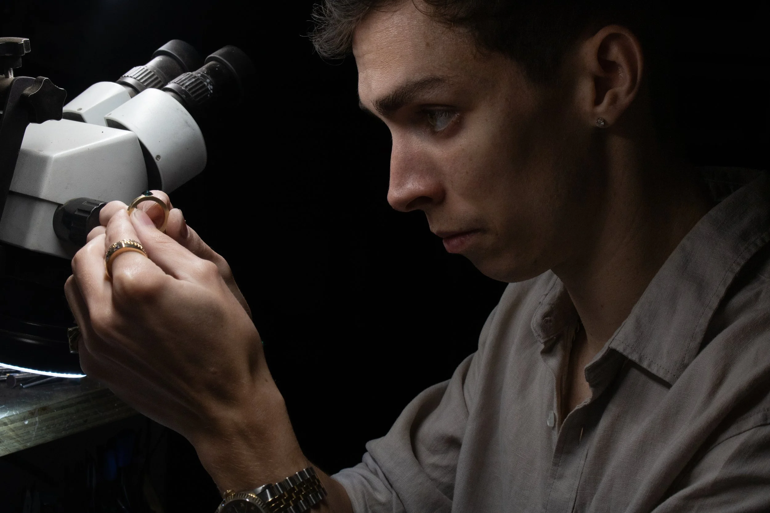 A person examining a microscope closely, adjusting the focus.