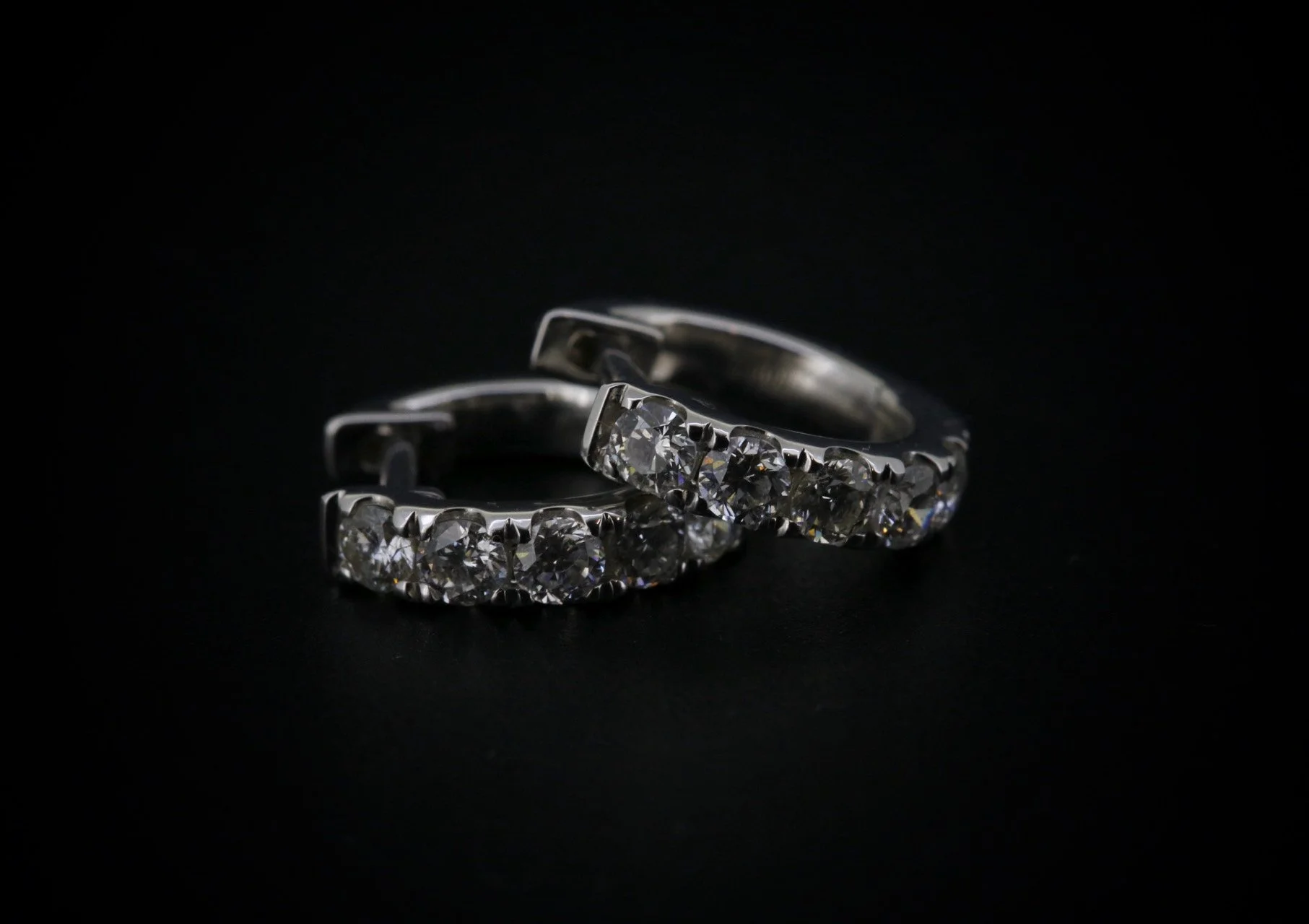 Two silver rings with numerous small diamonds on a black background.
