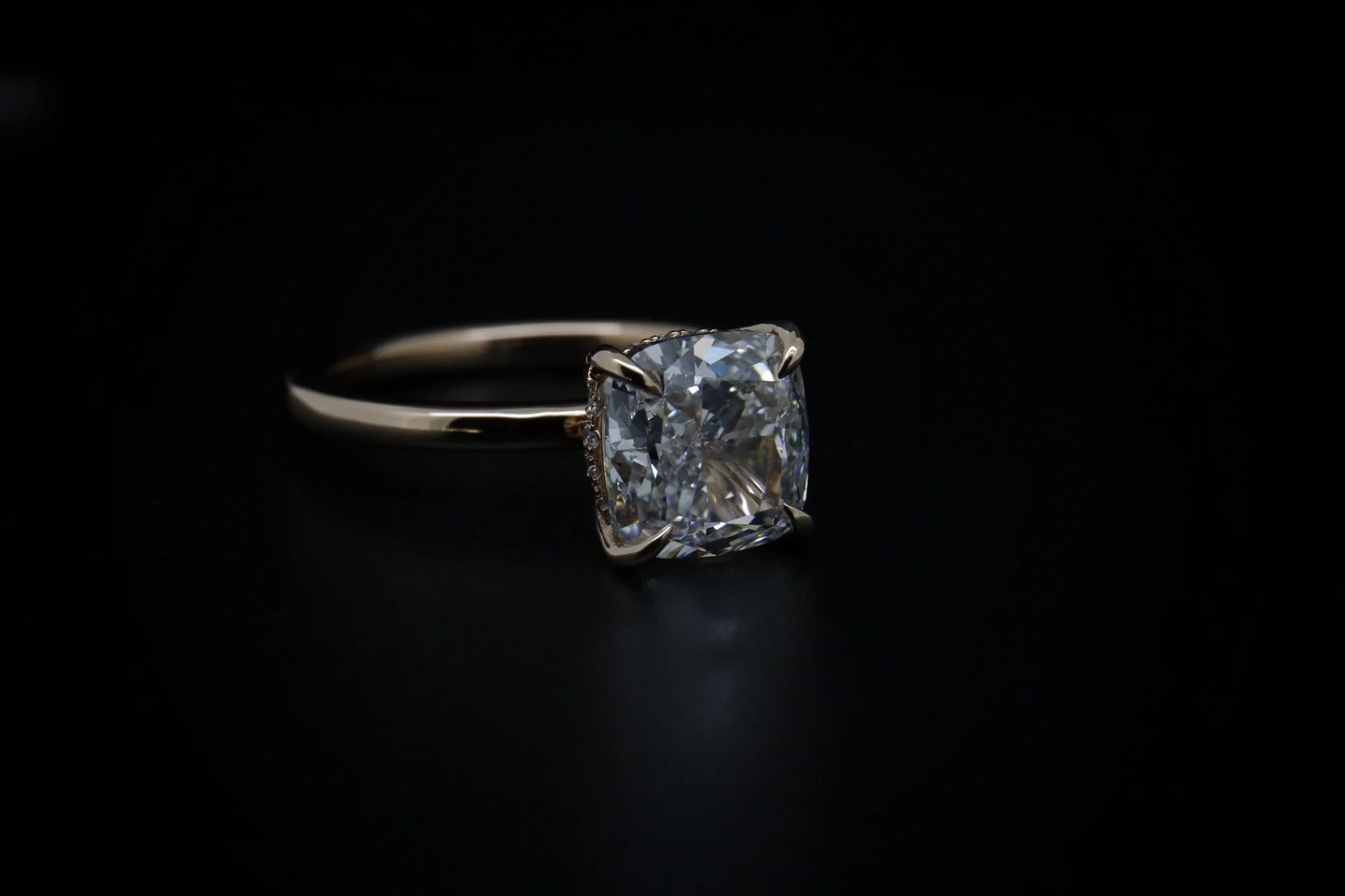 Close-up of a diamond engagement ring with a square-cut diamond on a black background.