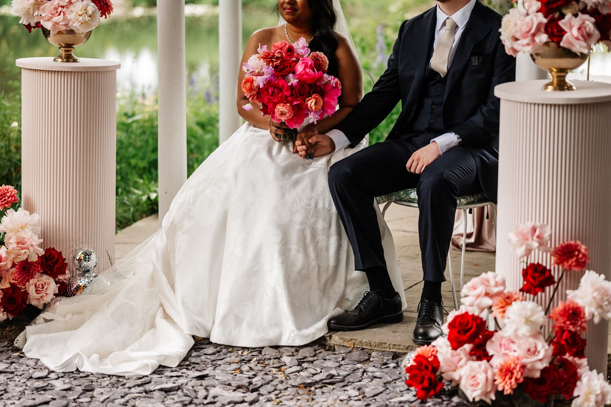 Wedding ceremony flowers on blush fluted plinths beside Diana and Sean at Preston Court
