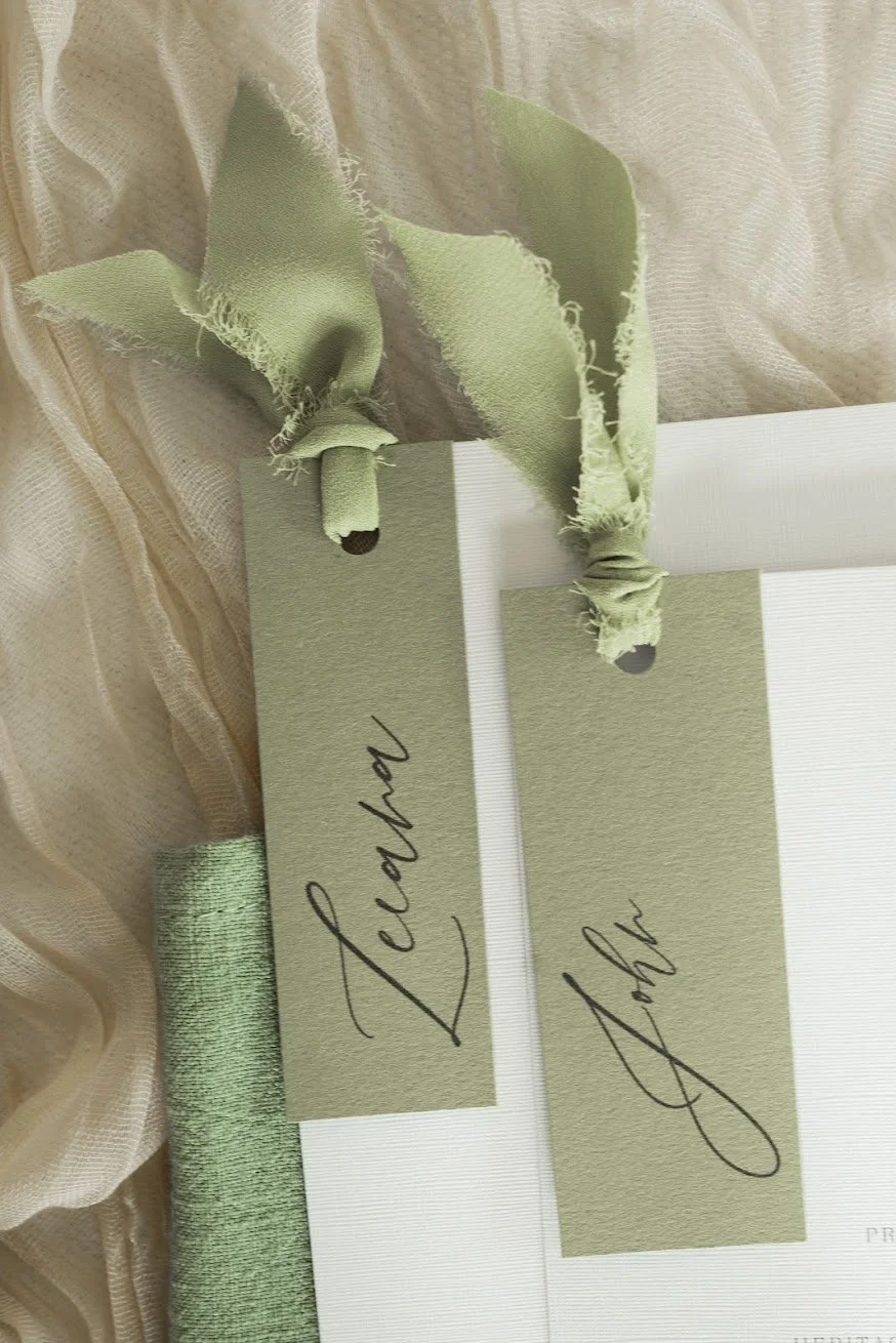 Sage-green personalised wedding place cards tied with textured ribbon