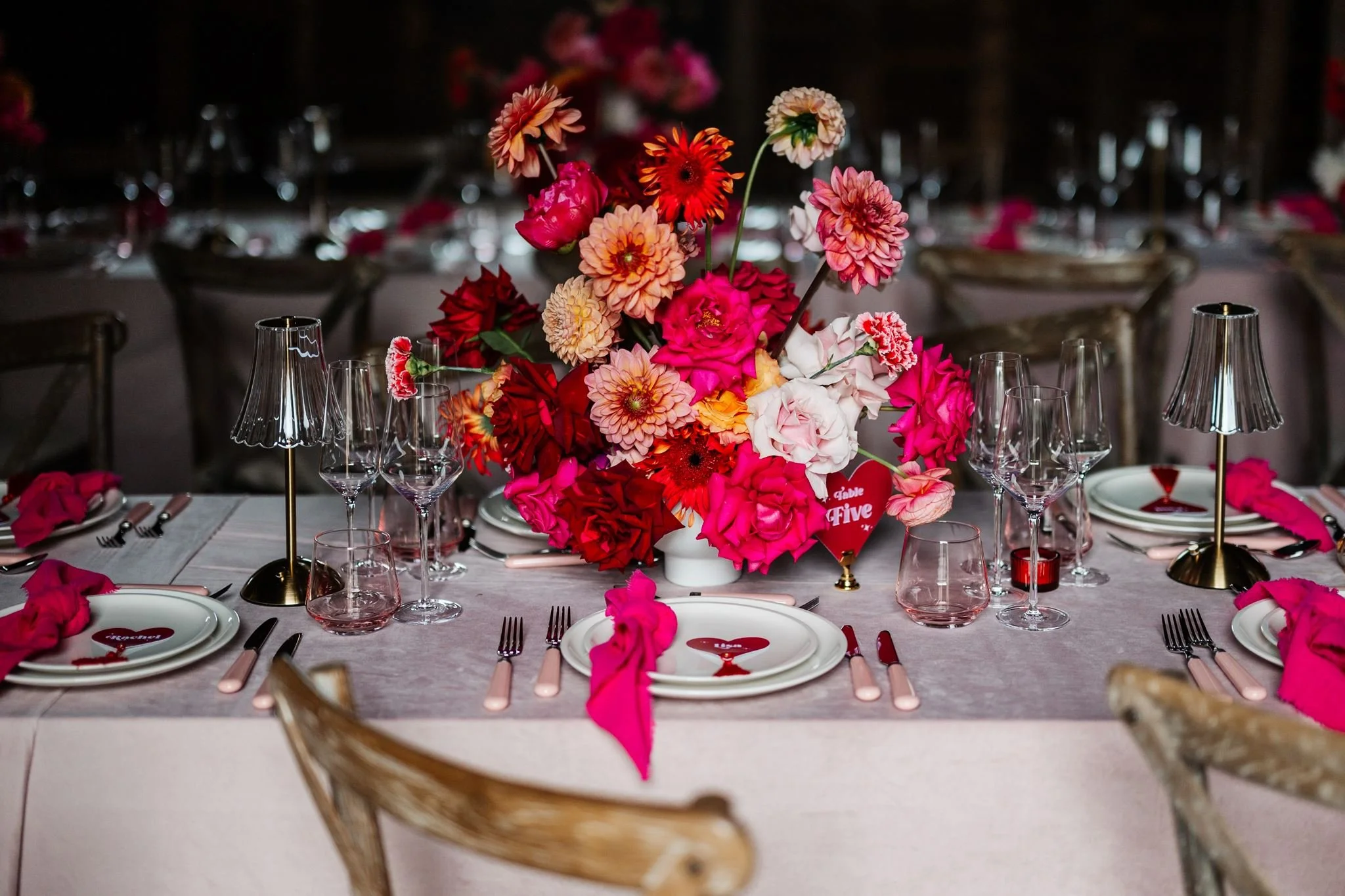 Colourful wedding floral centrepiece with a red heart table number and pink place settings