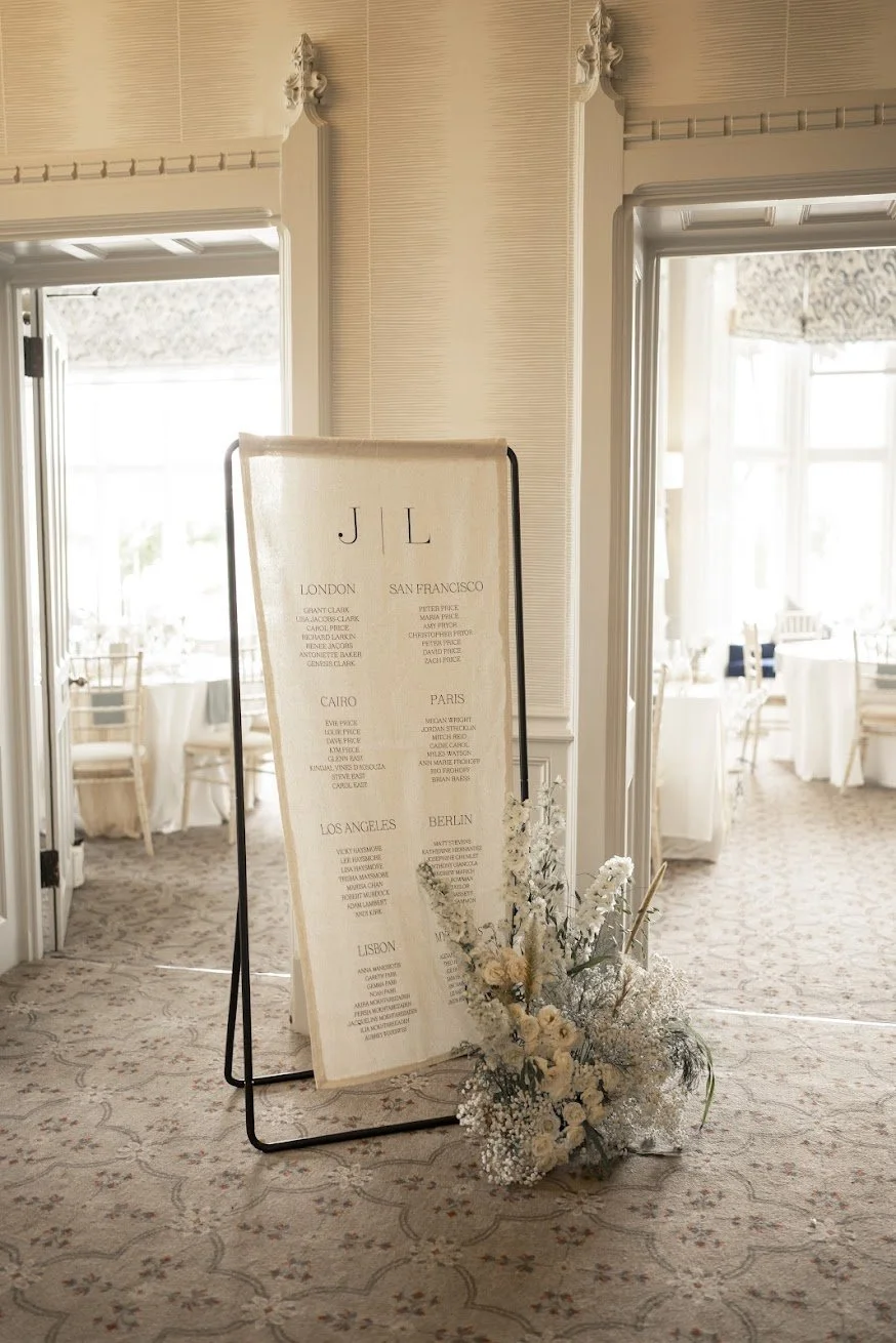 Bespoke fabric wedding seating plan on a black frame with romantic white flowers