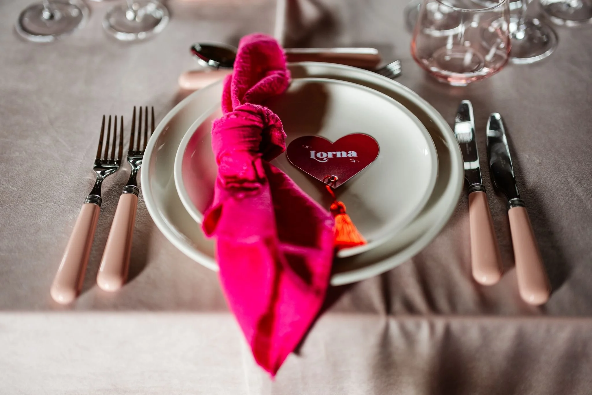 Personalised red heart wedding place name with an orange tassel, pink napkin and blush-handled cutlery