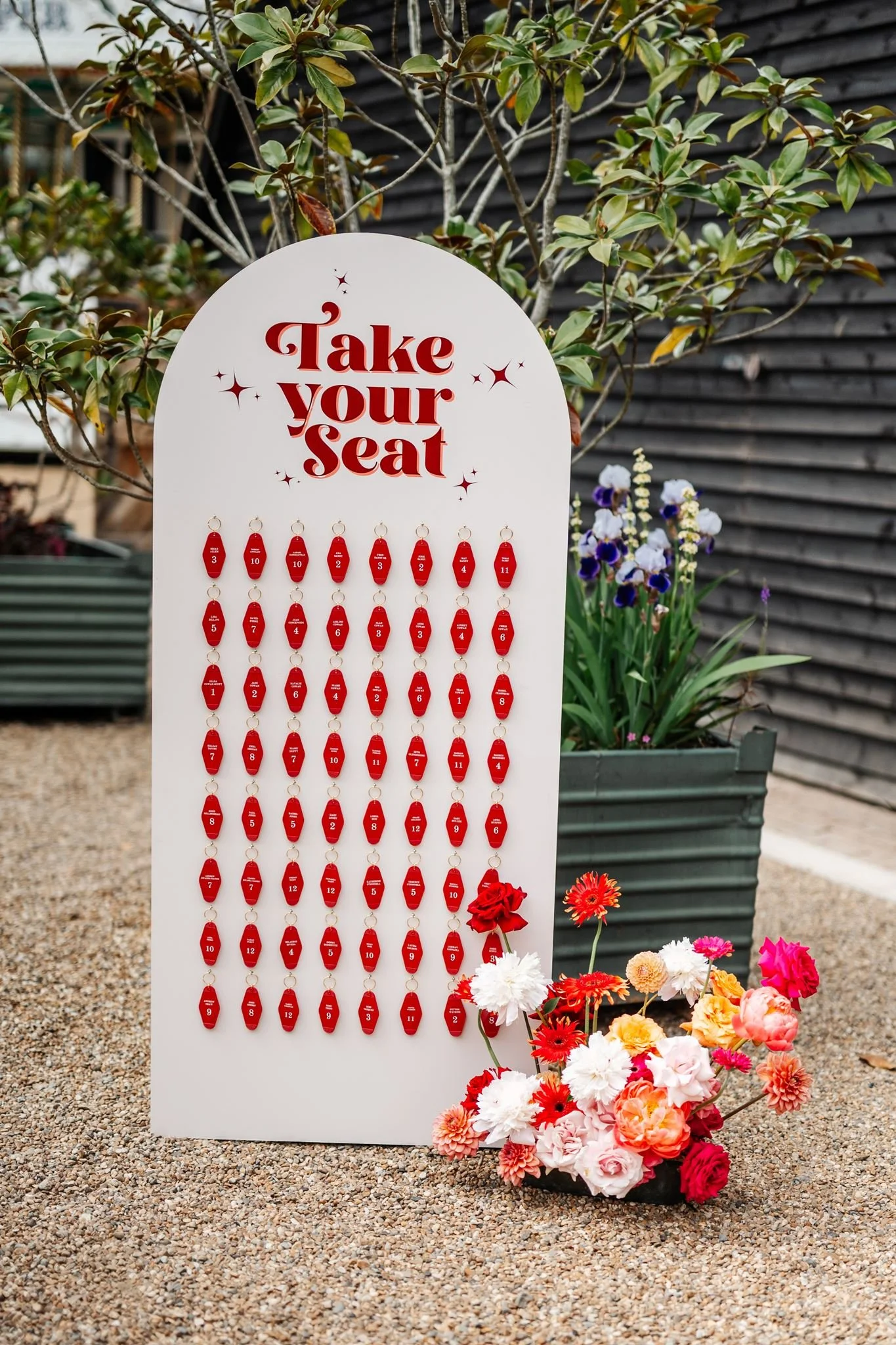 Vegas-inspired wedding seating plan with red motel keyrings and colourful flowers at Preston Court