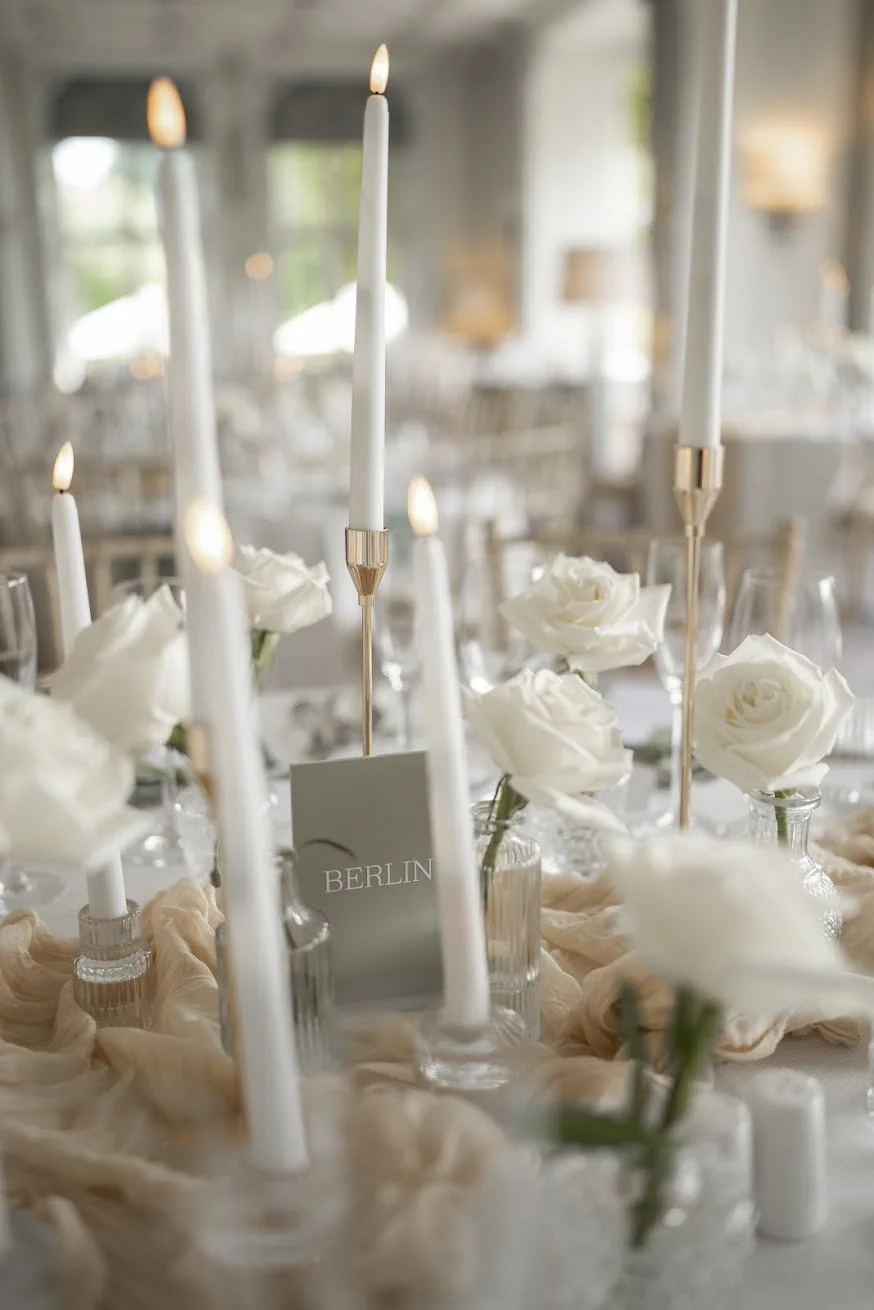 White rose bud vases and tall tapered candles on a luxury wedding tablescape