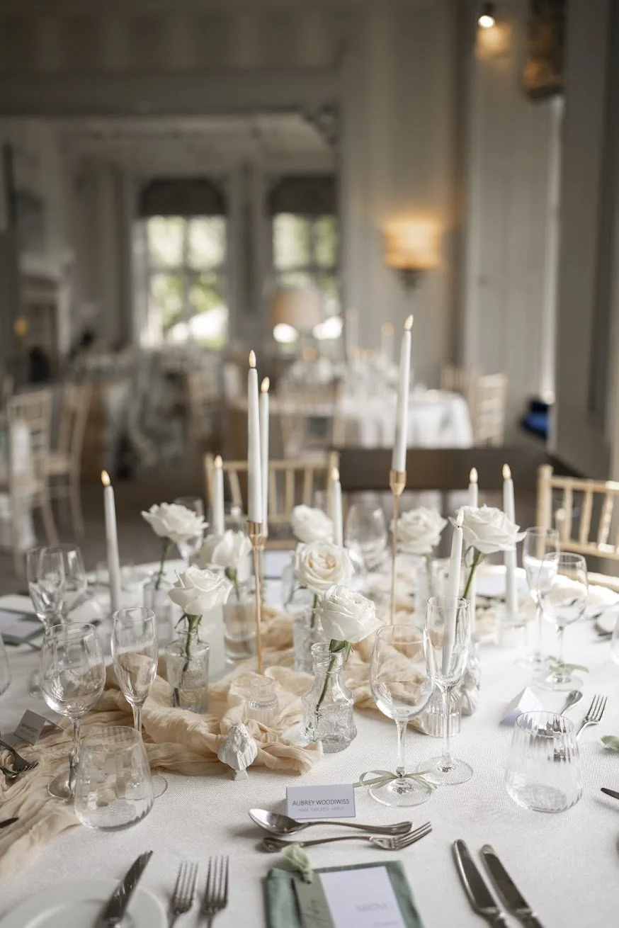 Elegant wedding breakfast table with white roses, tapered candles and soft fabric styling