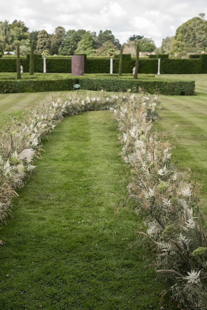 Meadow-style white wedding flowers lining an outdoor ceremony walkway at Hever Castle