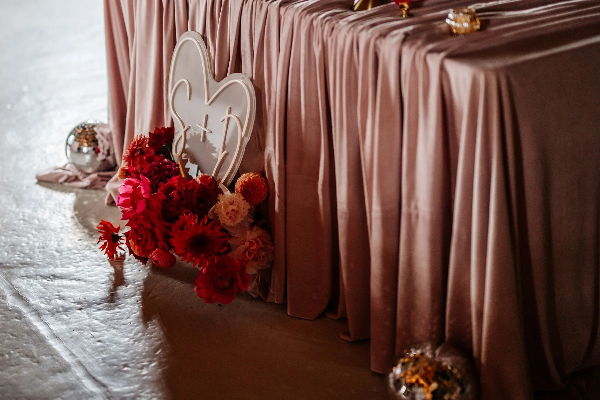 Blush wedding table draping with a colourful floral arrangement and decorative heart