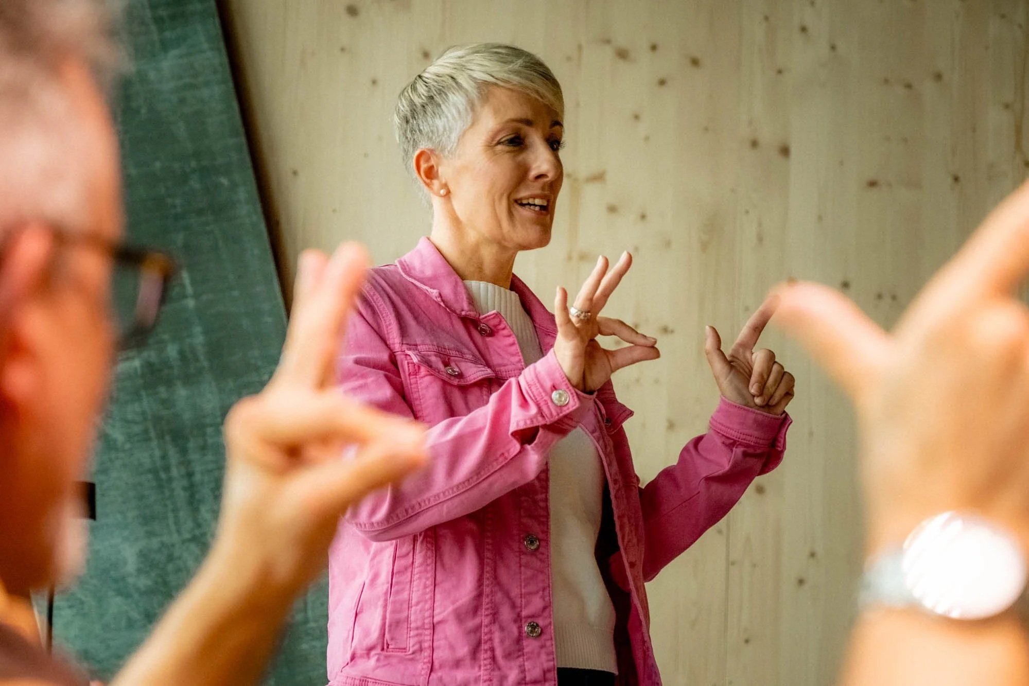 Gedächtnistrainerin Petra Oggenfuss in pinker Jacke zeigt eine Übung zur Verbesserung der Gehirnleistung vor