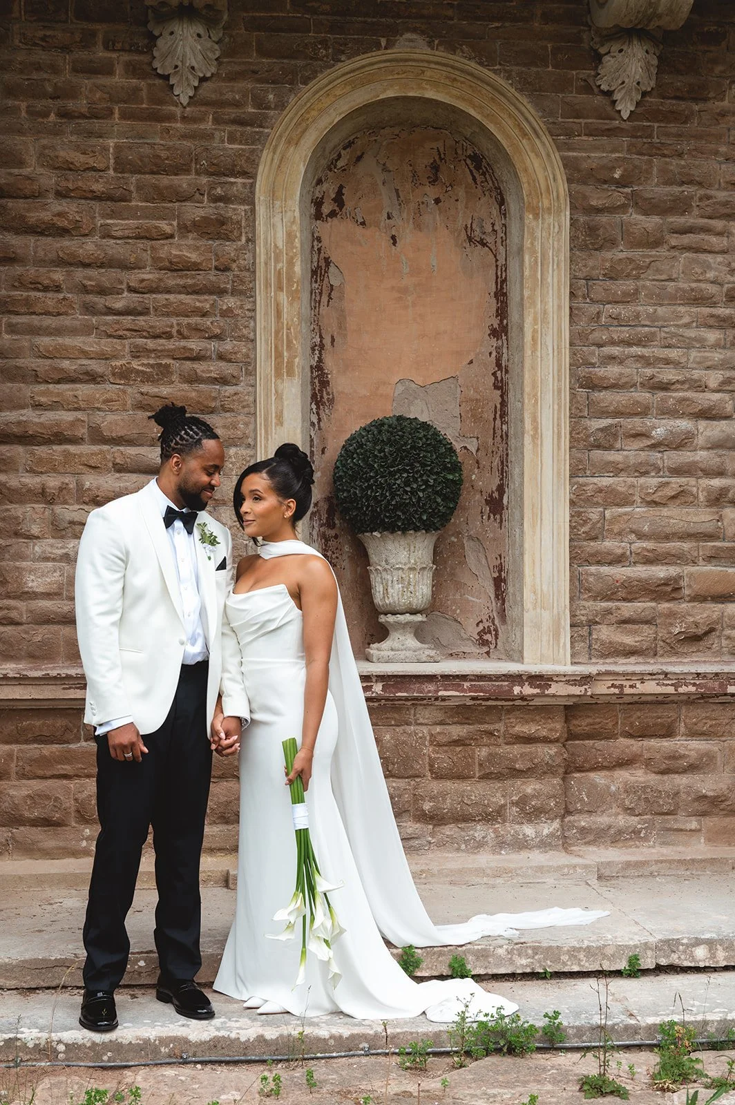 bride and groom holding hands posing outside their wedding venue