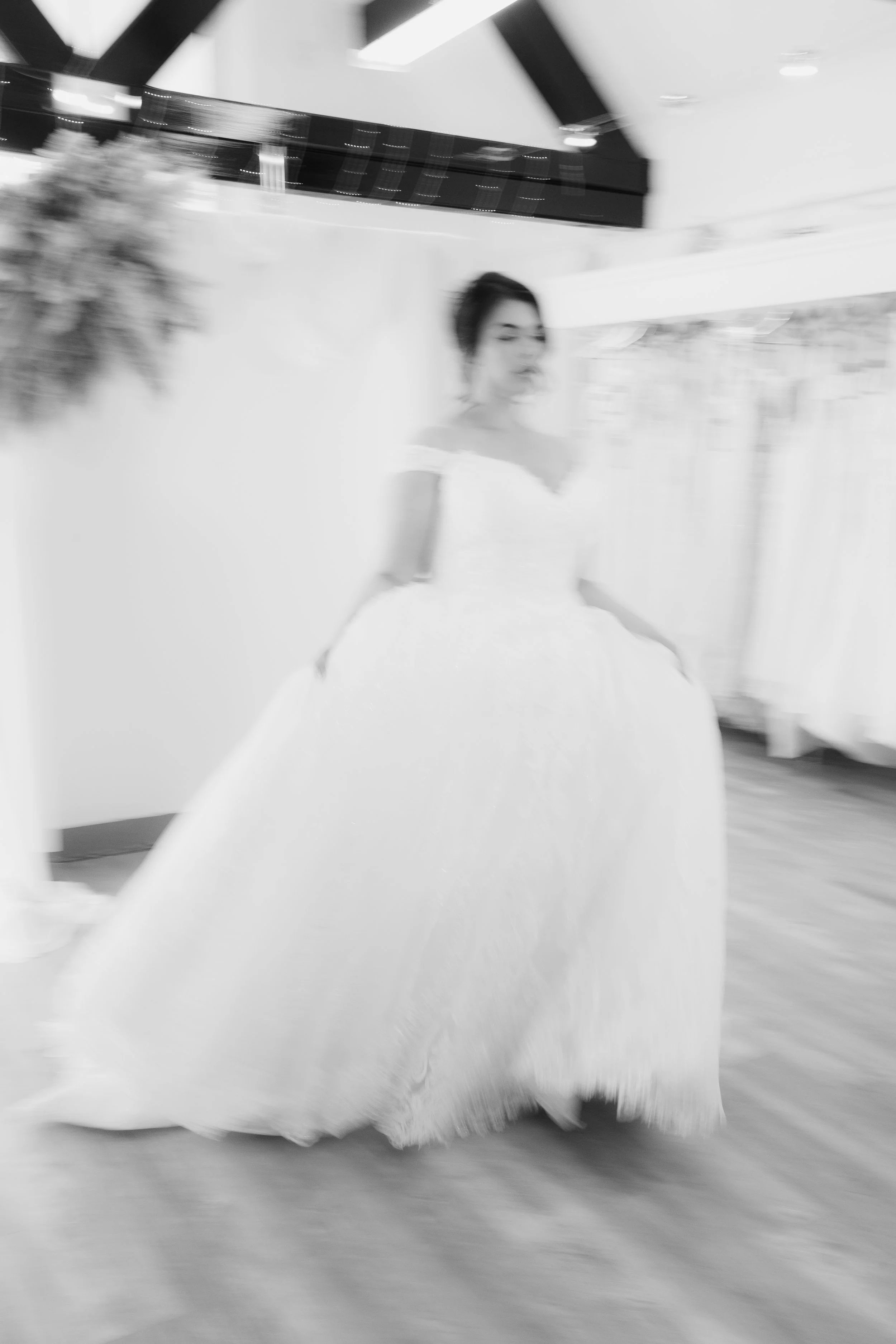A woman in a white wedding dress standing indoors with a blur effect.