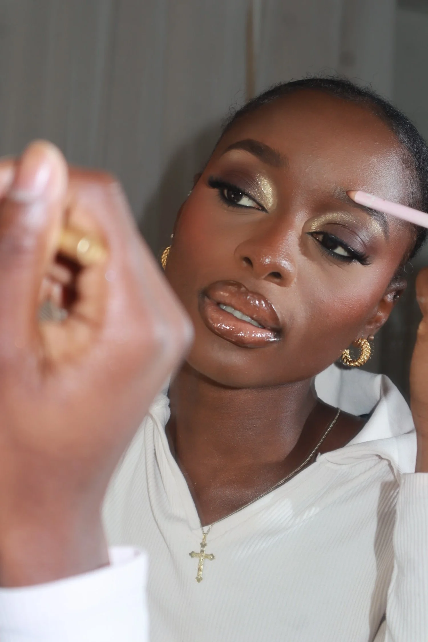 A woman with makeup applying eye shadow in front of a mirror.