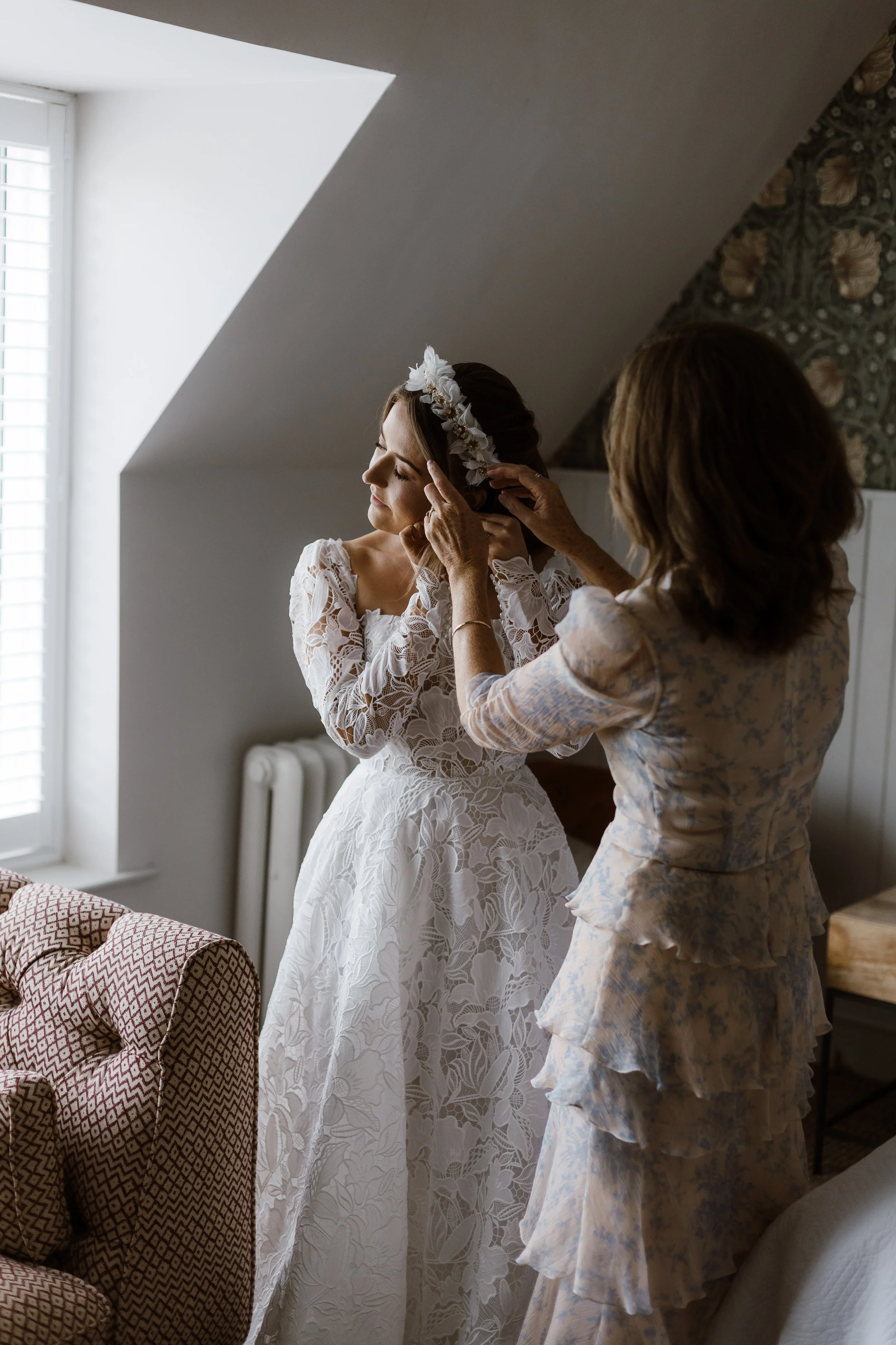 bride and mother of the bride helping bride put earing on