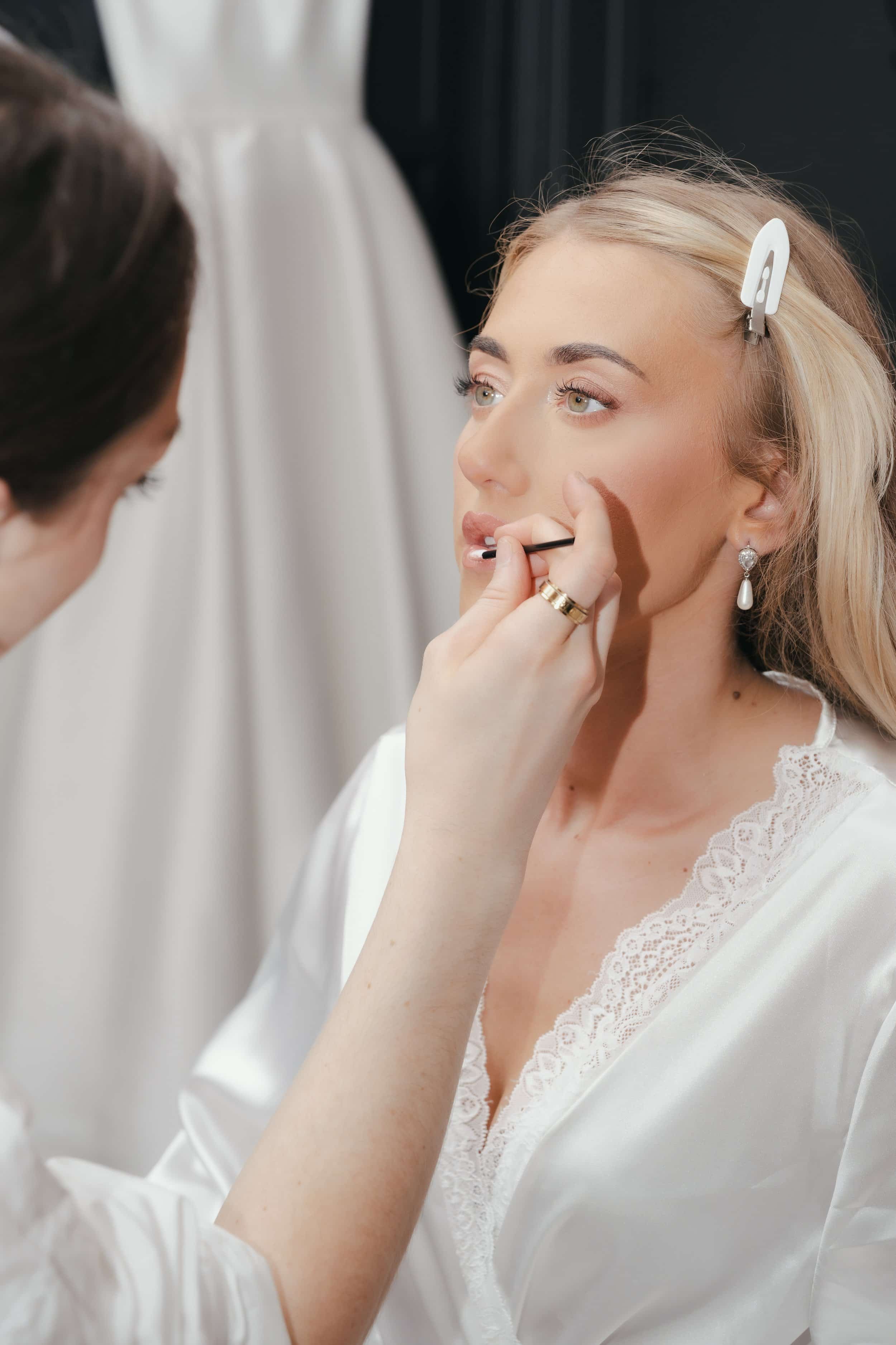 Blonde women having her makeup done by a bridal makeup artist 