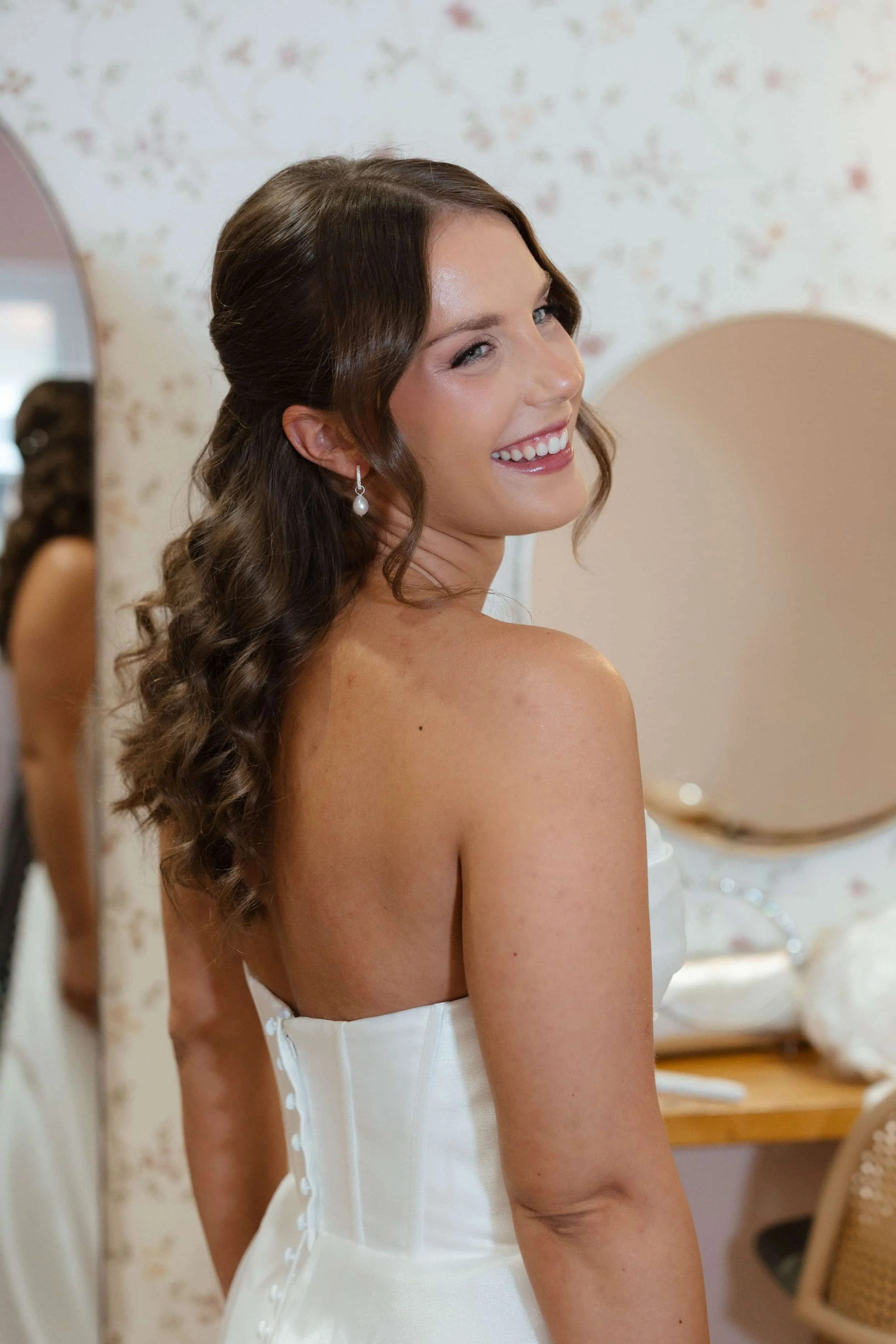 Brunette women looking over shoulder wearing a wedding dress and with bridal makeup on 