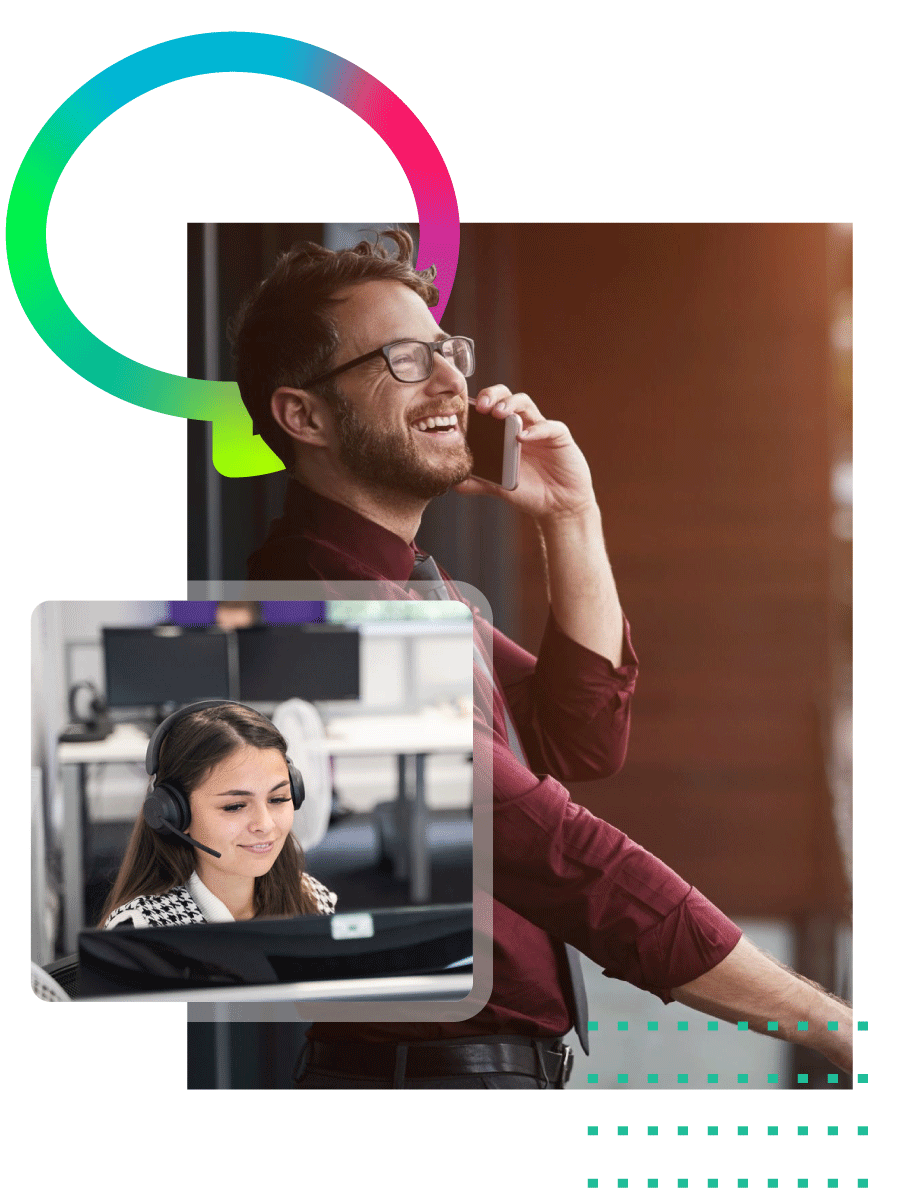 A man with glasses and a beard on a phone call in an office, with a woman in a headset working at a computer in front of him.
