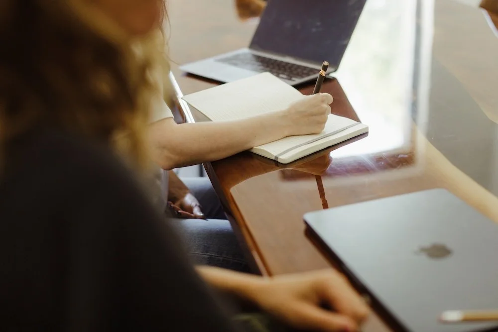 Person takes notes at desk in meeting
