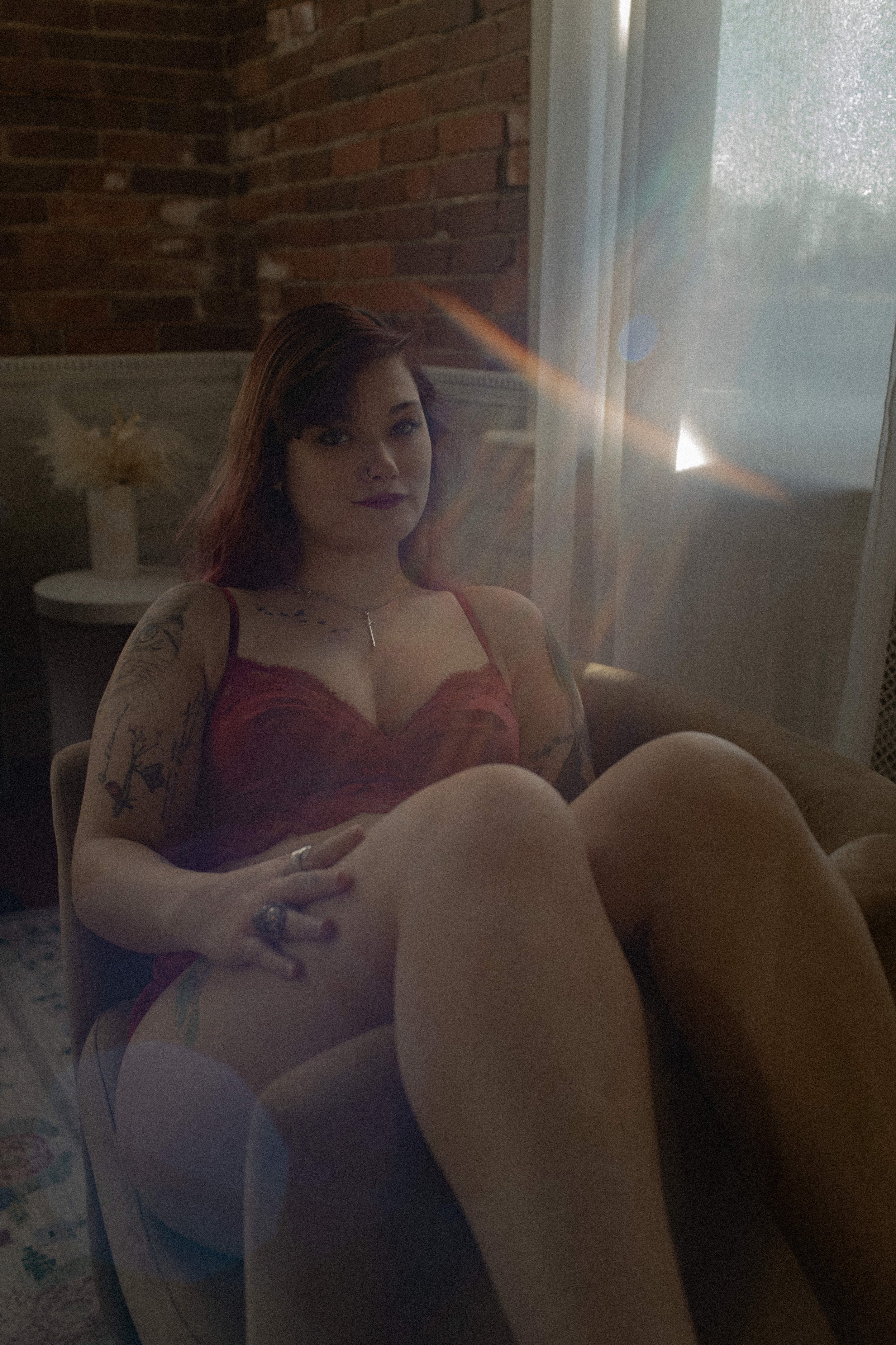 sun flare image boudoir red lingerie girl posing on tan chair