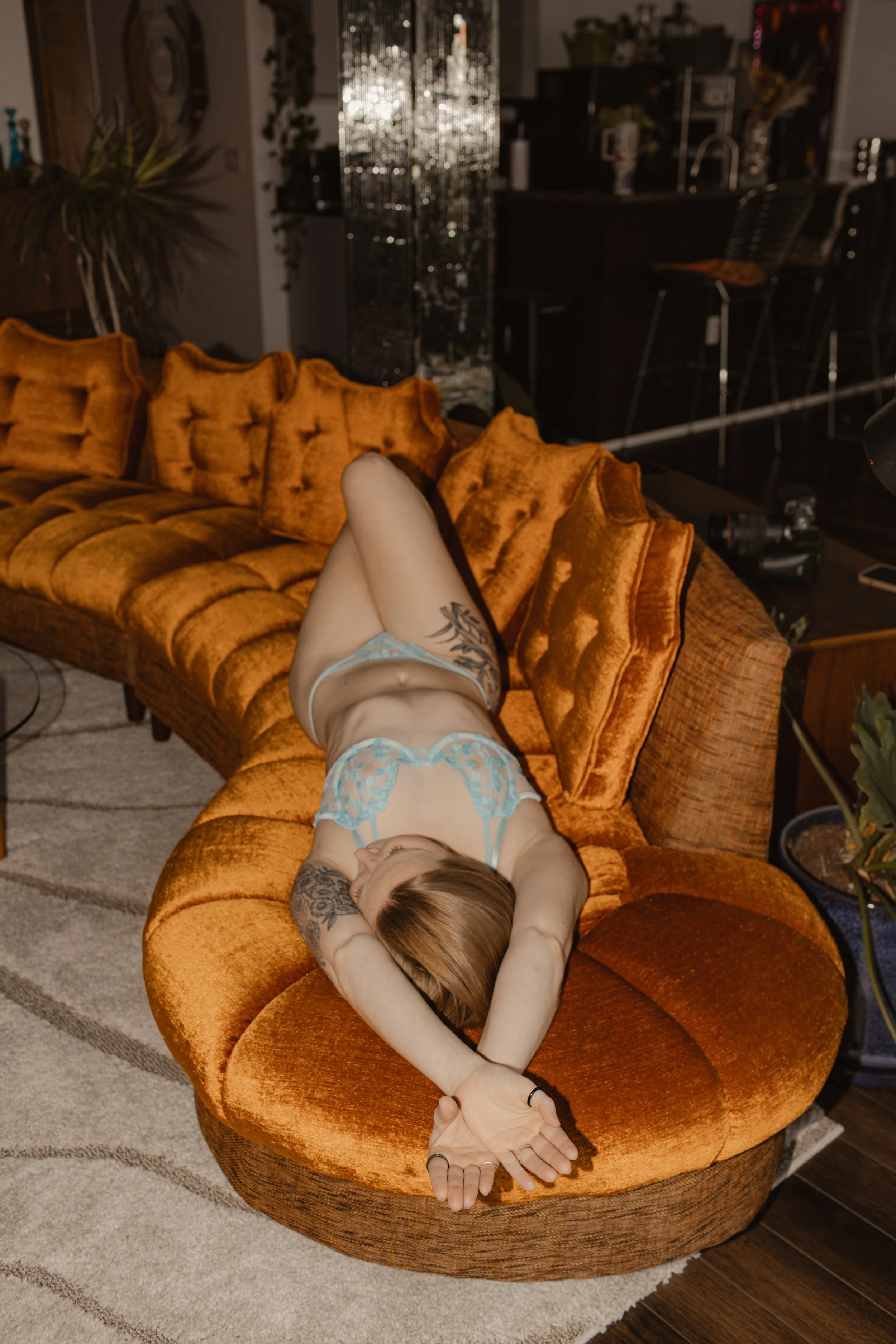 girl posing on orange couch in matching blue lingerie set