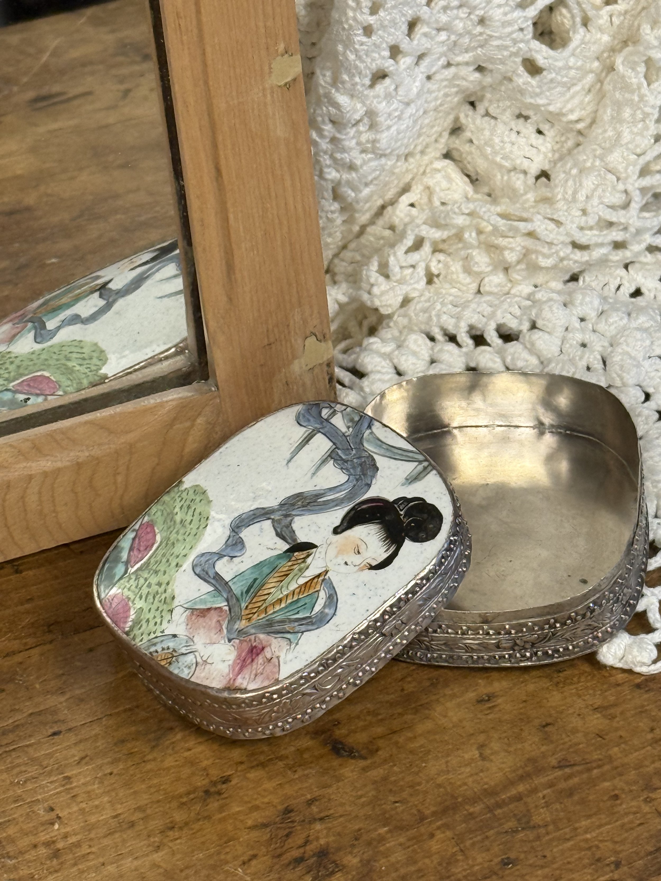 Vintage hand-painted porcelain trinket box shown open, silver-toned repoussé metal interior and base with engraved floral detailing, decorative storage box with artisan craftsmanship