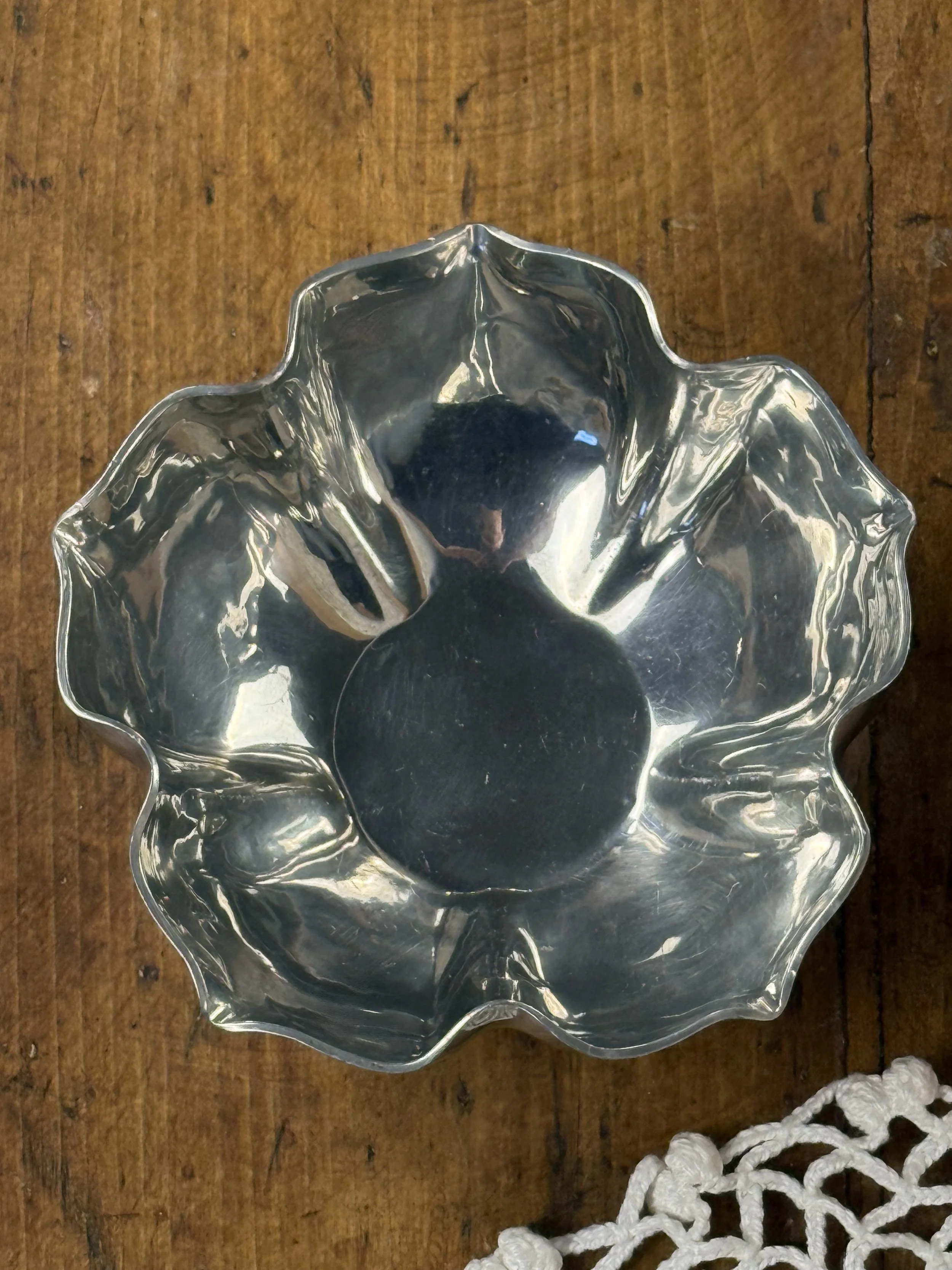 Top-down view of vintage silver fluted bowl, symmetrical scalloped design and softly rippled metal interior