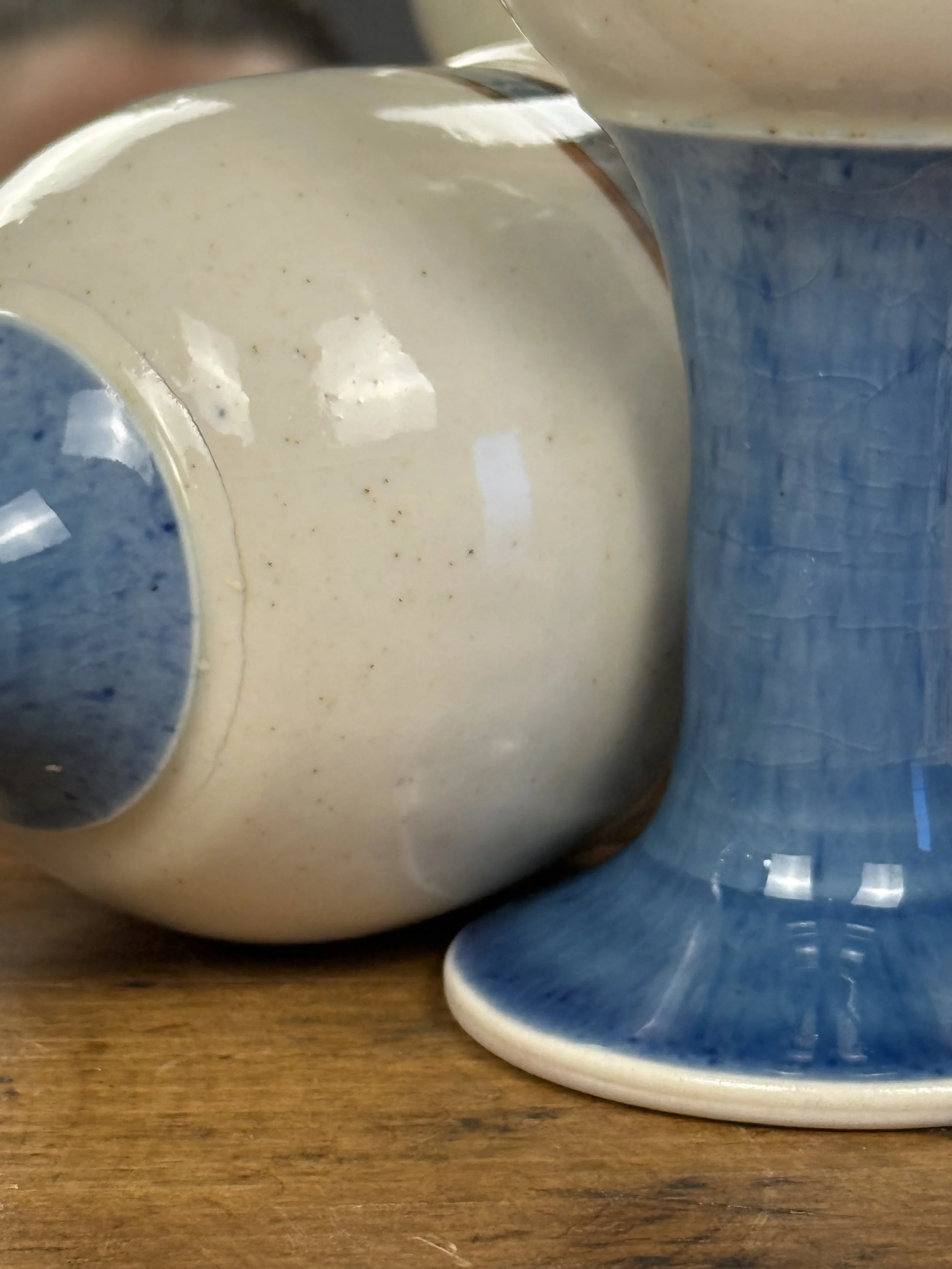 Close-up vintage stoneware glaze, cream ceramic bowl with blue crackle stem, handcrafted pottery texture detail