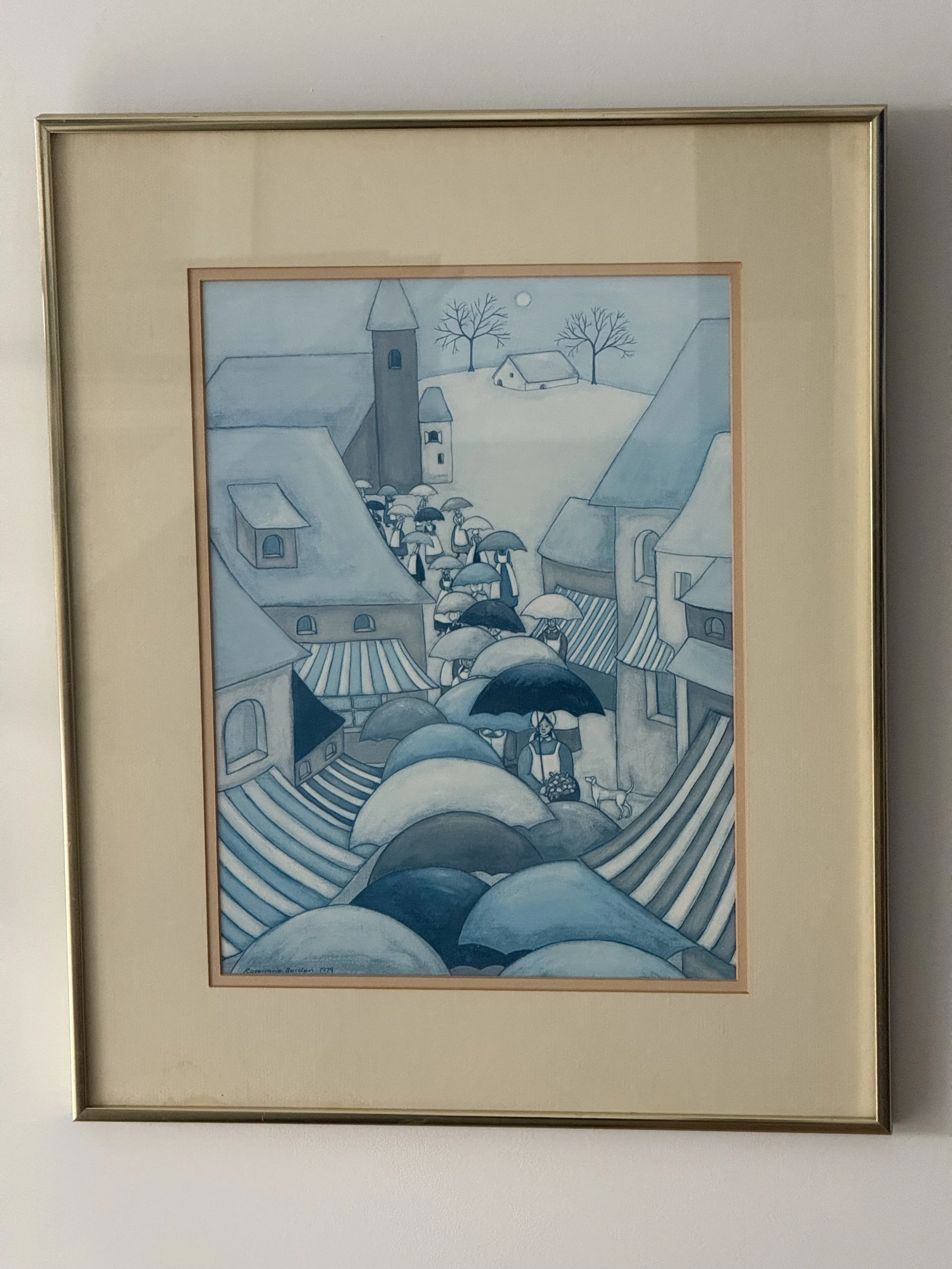 Vintage naïve folk art drawing of an umbrella procession through a village street, rendered in layered blue tones, signed and dated 1979, matted and framed with gold-tone frame