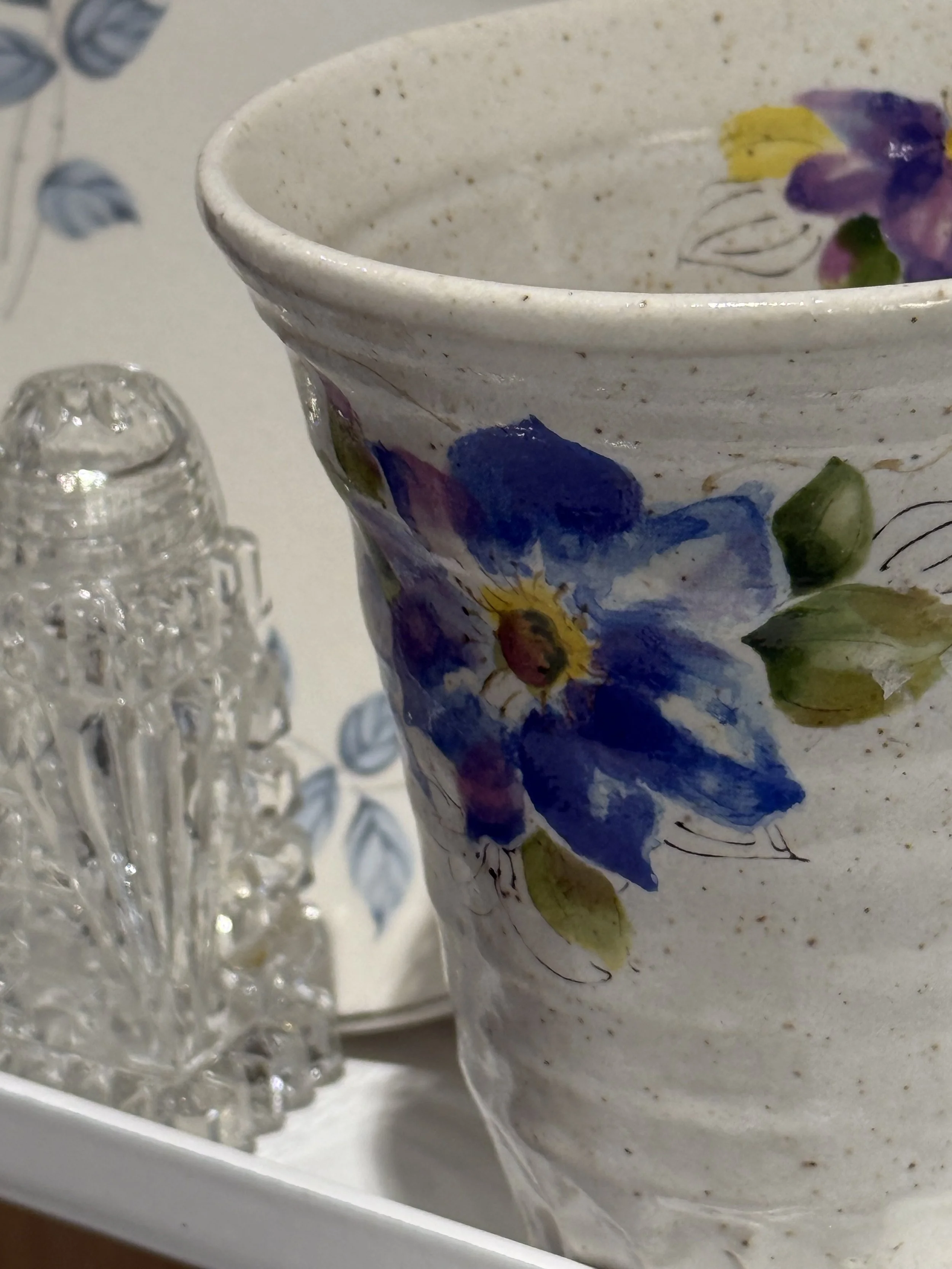 Side detail of hand-painted Japanese stoneware vase highlighting floral motif, subtle glaze texture, and organic ceramic form styled on shelf