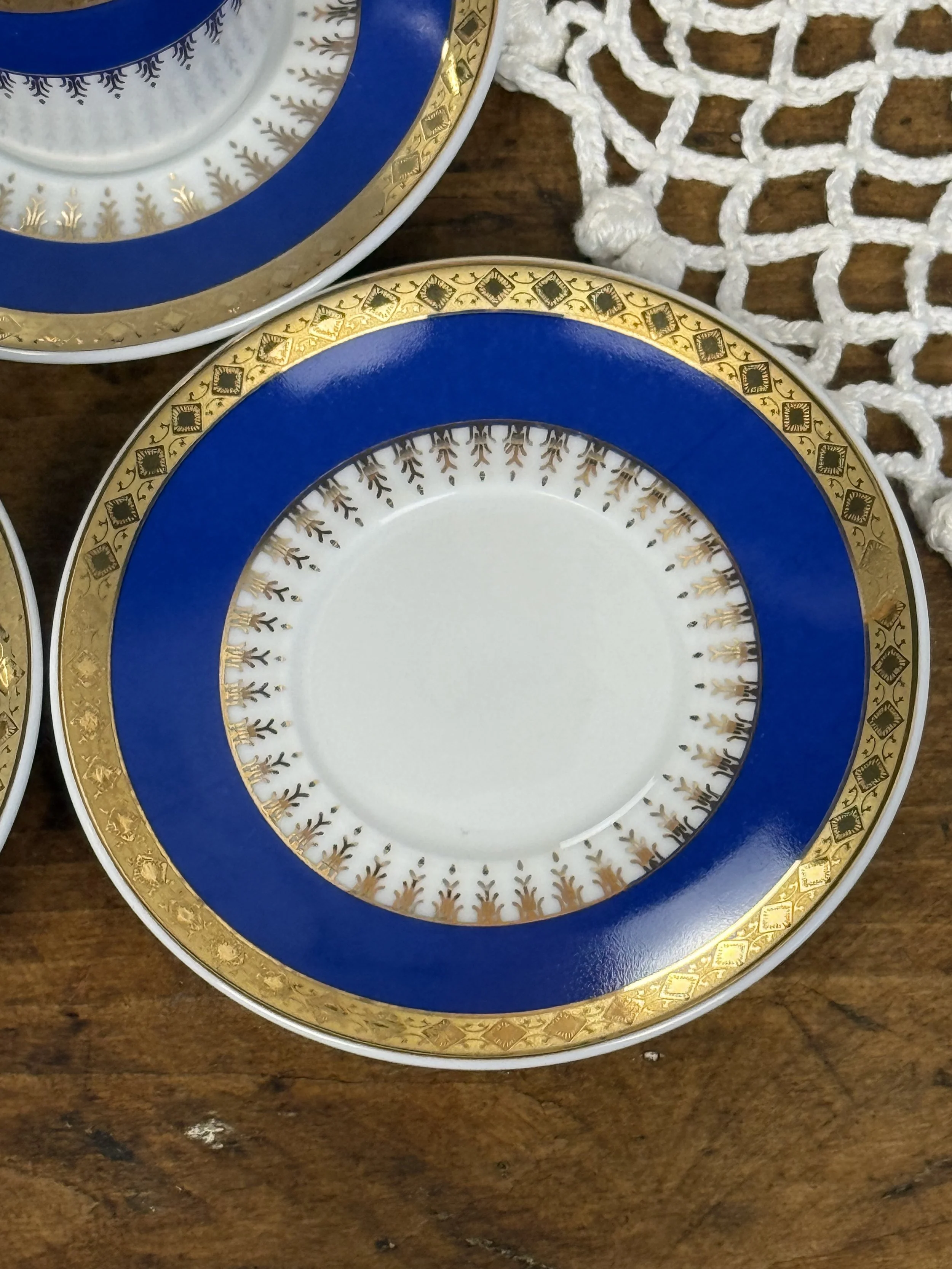Top view of vintage porcelain saucer with cobalt blue border and gold decorative pattern, formal espresso service plate