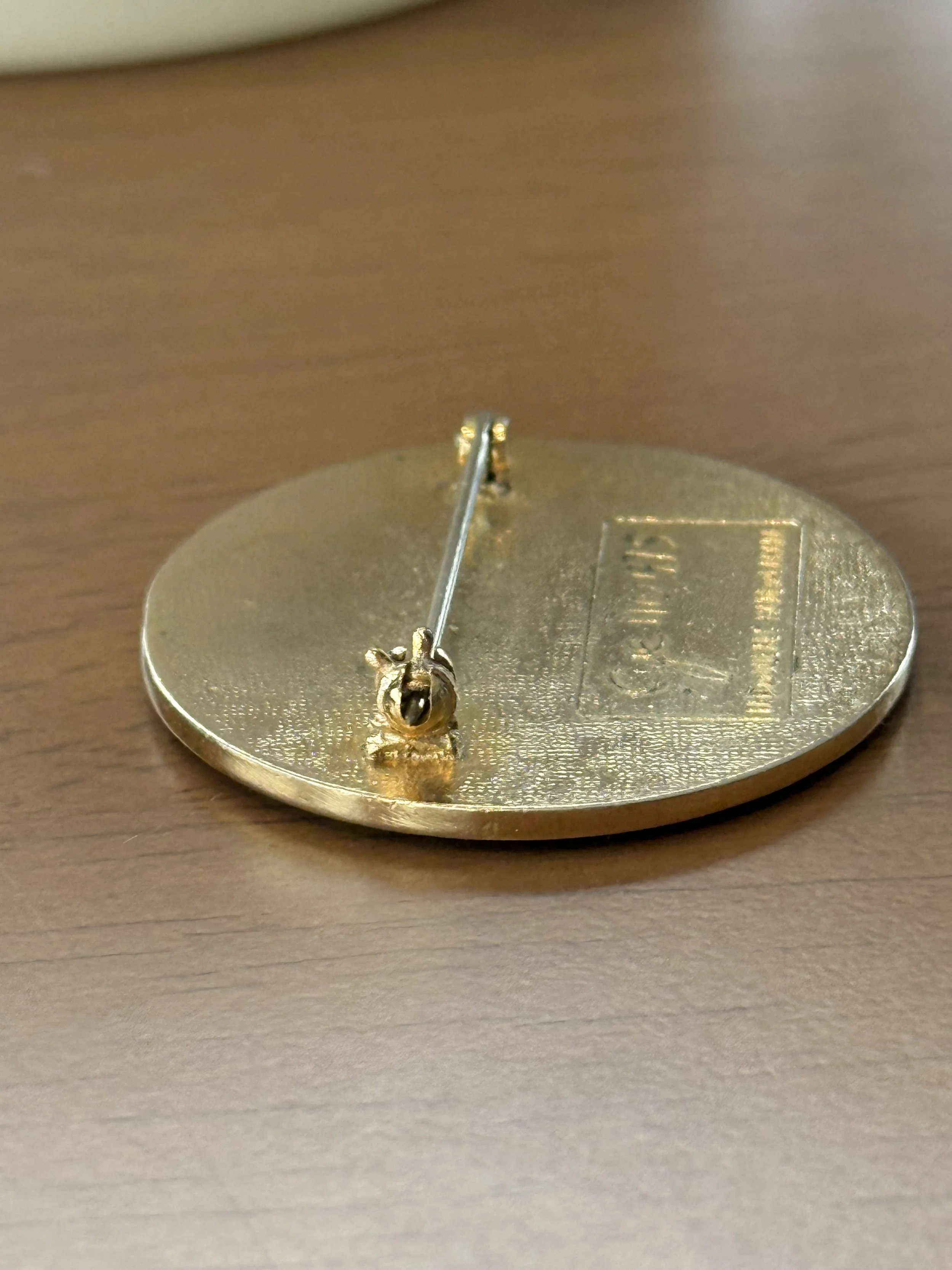 Rear view of oval brass enamel bird brooch showing pin mechanism and stamped signature, vintage Canadian artisan jewelry