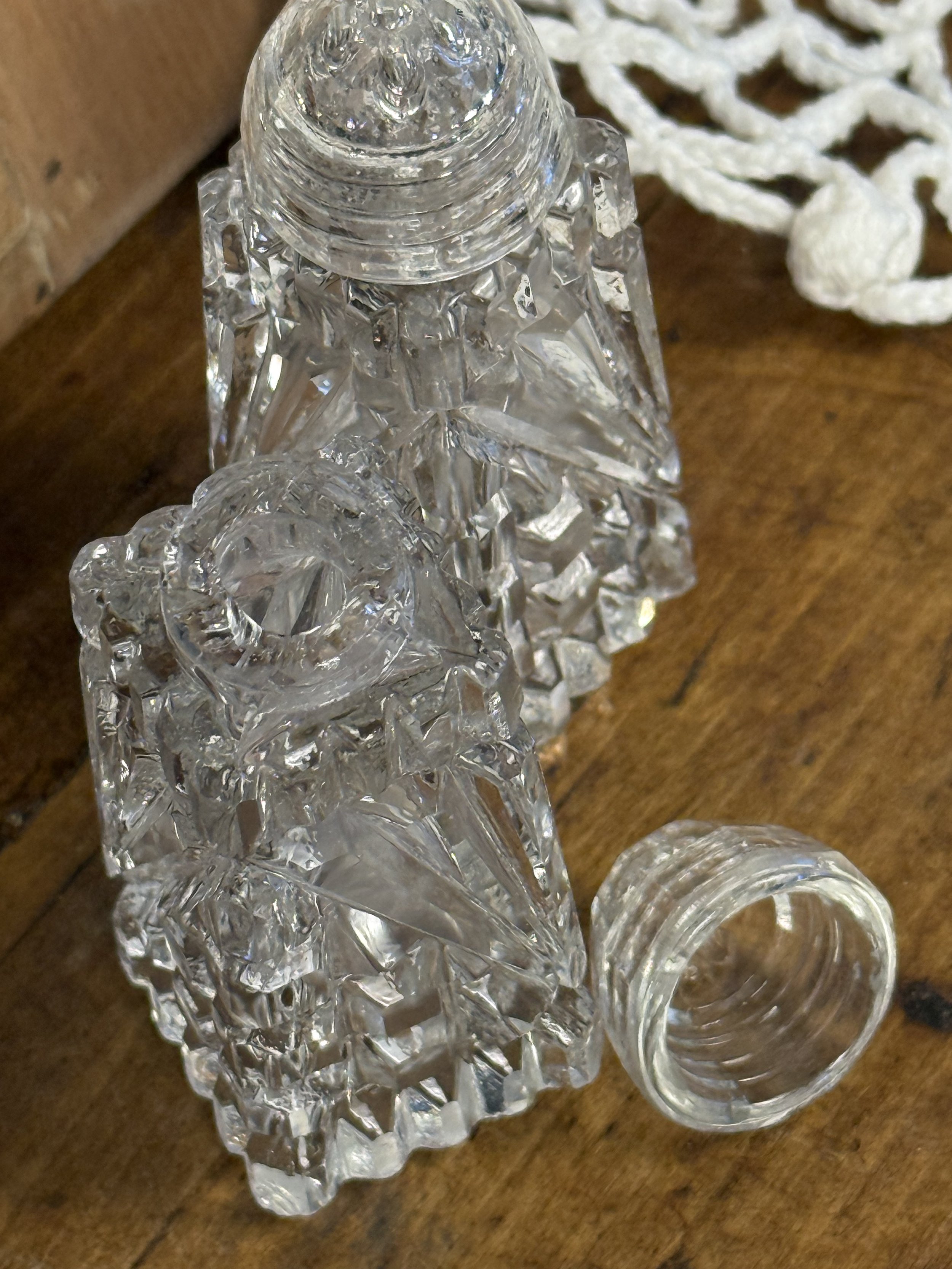 Disassembled vintage glass salt and pepper shakers showing threaded glass lid and interior opening, clear cut glass construction, functional retro kitchenware