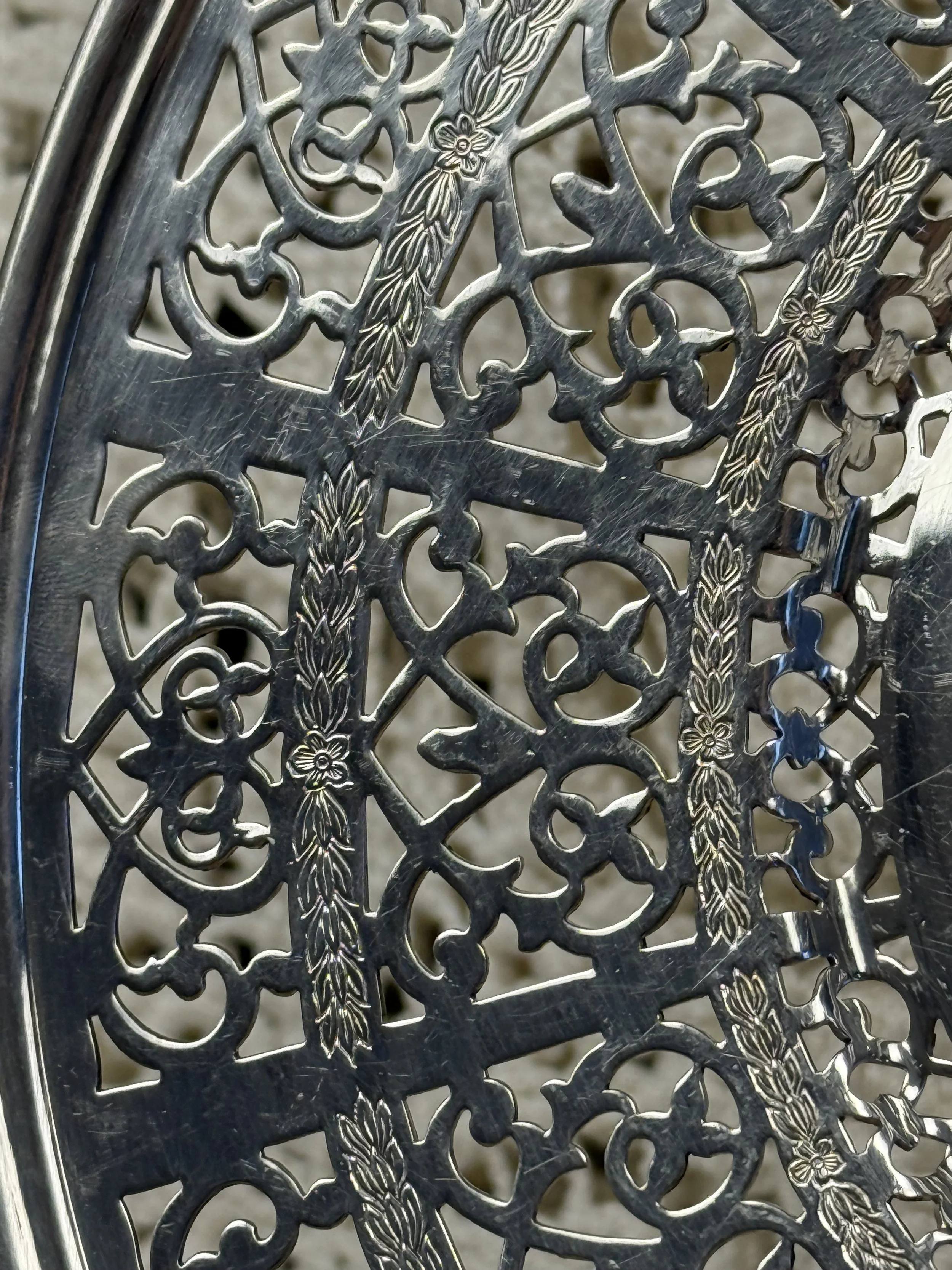 Close-up of pierced silverplate rim with ornate scroll and floral lattice detailing, vintage Warwick Plate craftsmanship