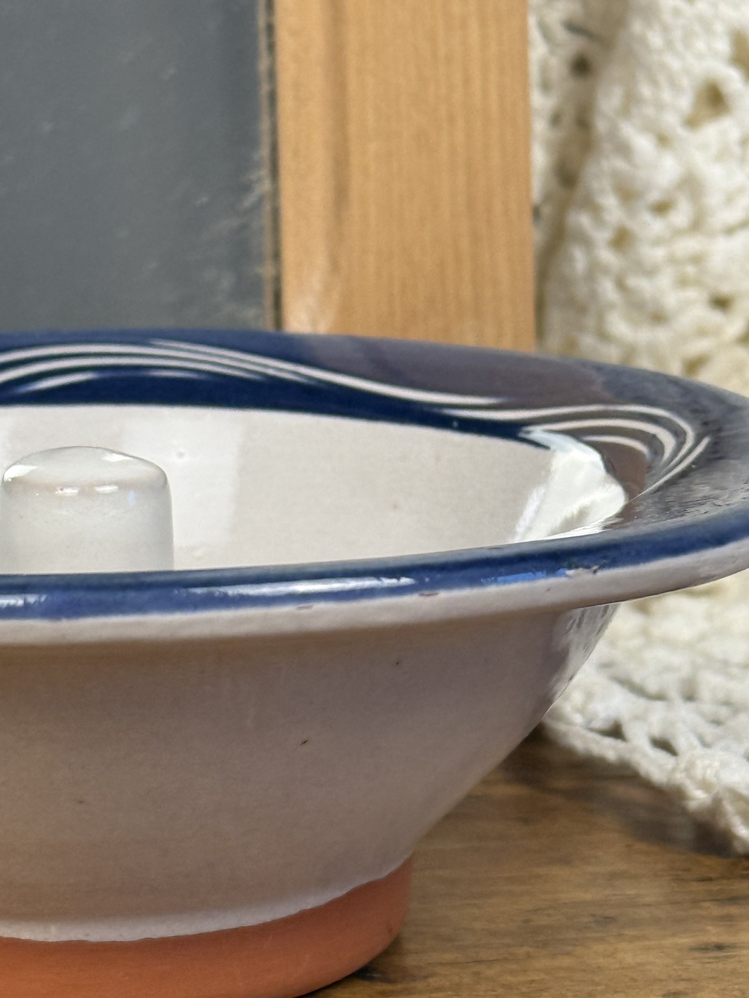 Side view of vintage terracotta apple baker showing navy blue rim, glazed interior, unglazed clay body, raised chimney baking dish for apples and pears