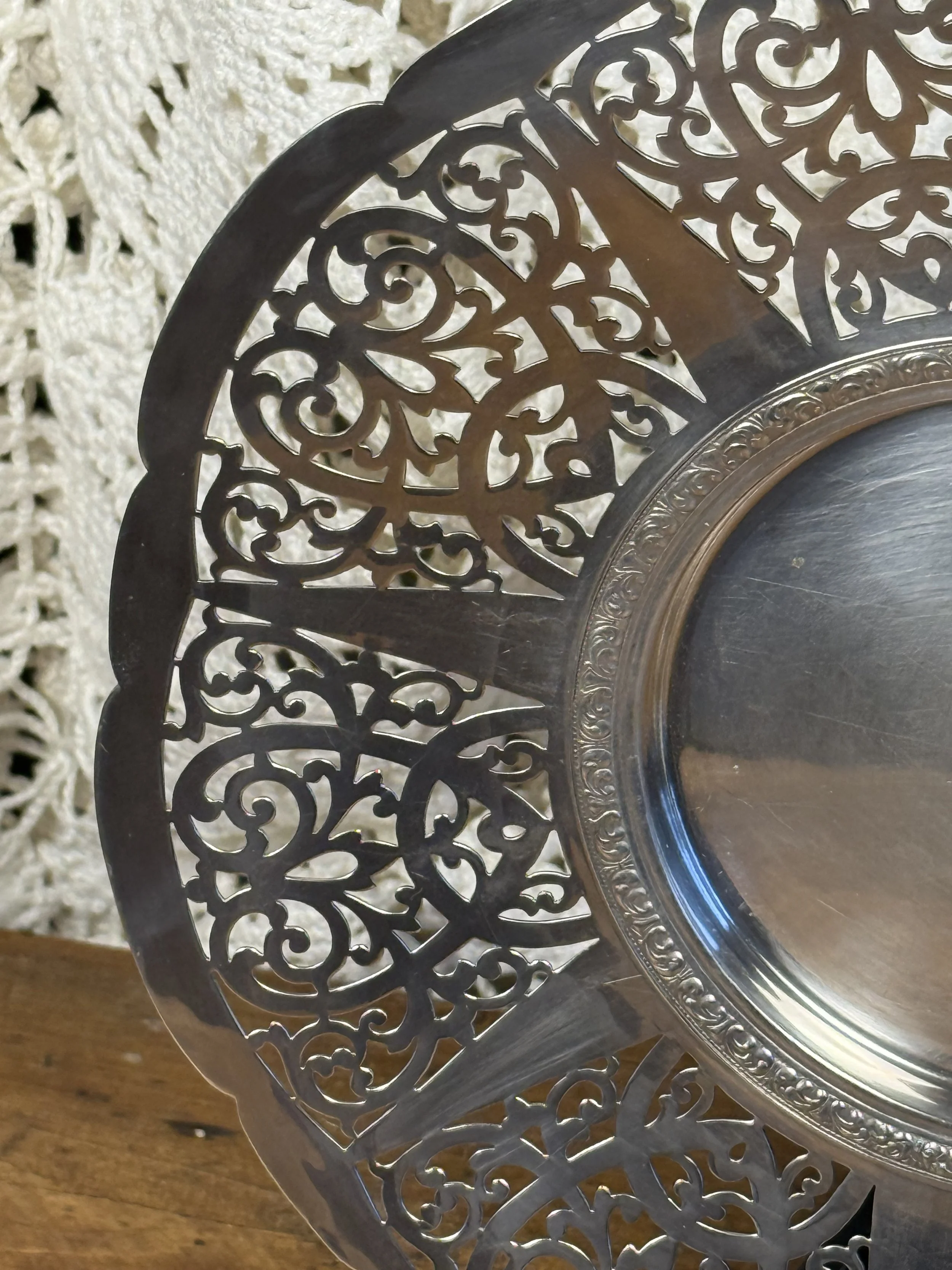 Side detail of pierced silverplate serving plate highlighting scalloped edge and layered openwork design, reflective silver finish