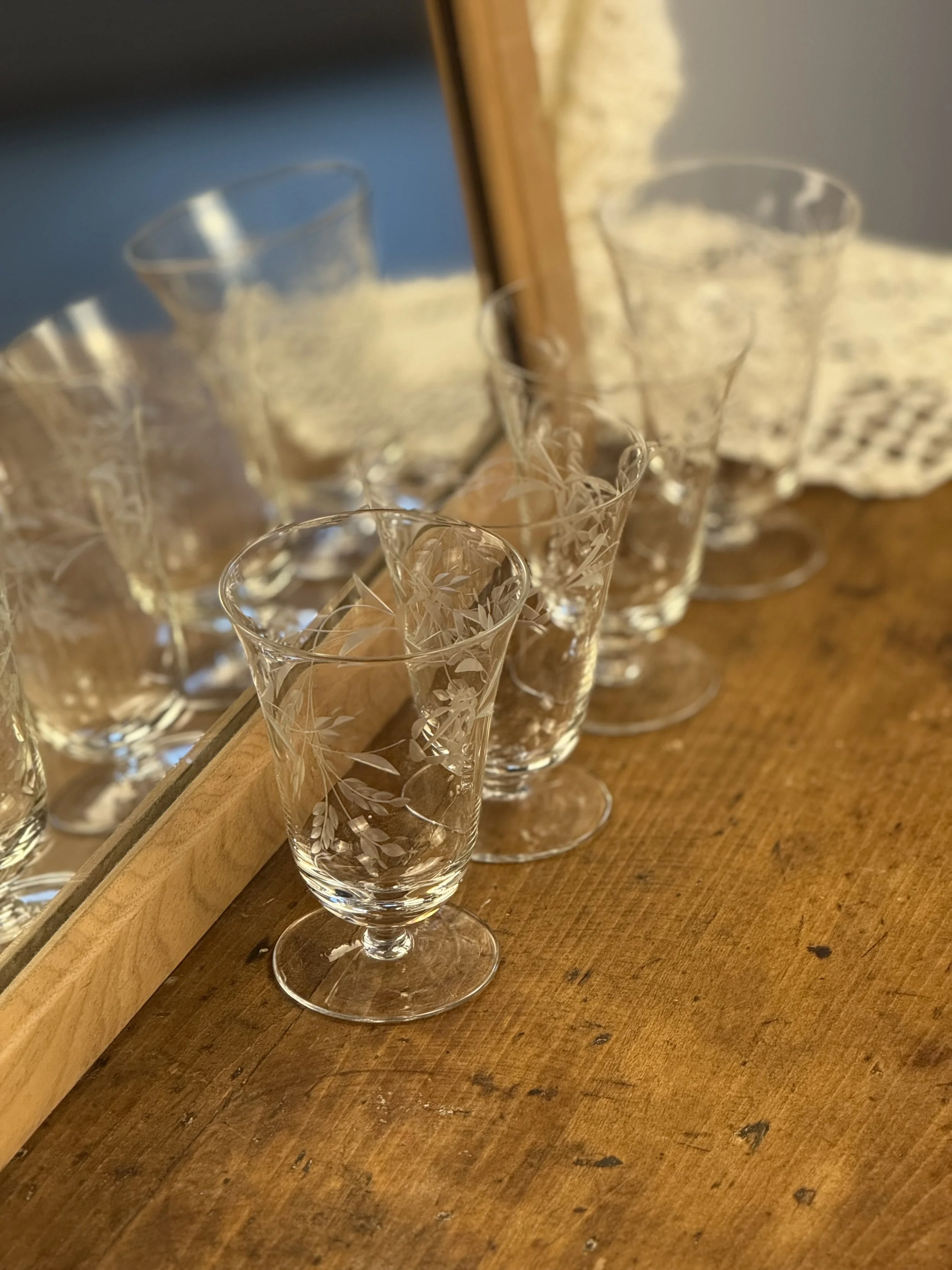 Vintage etched floral cocktail glasses set of four on wooden surface, clear stemmed glassware with delicate botanical leaf engraving, mid-century barware styling