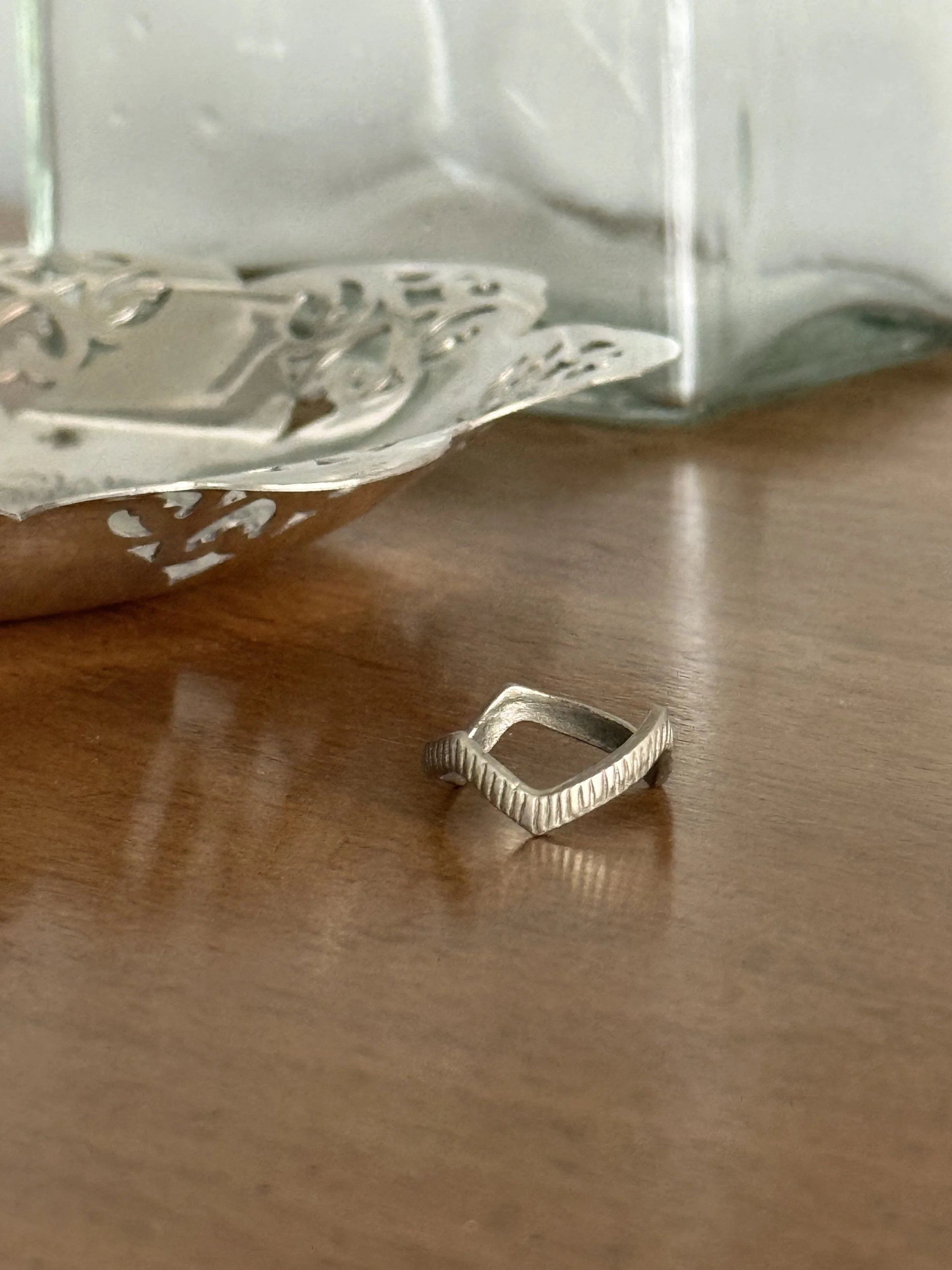 Vintage minimalist silver open band ring displayed upright on cone stand, architectural modernist jewelry design