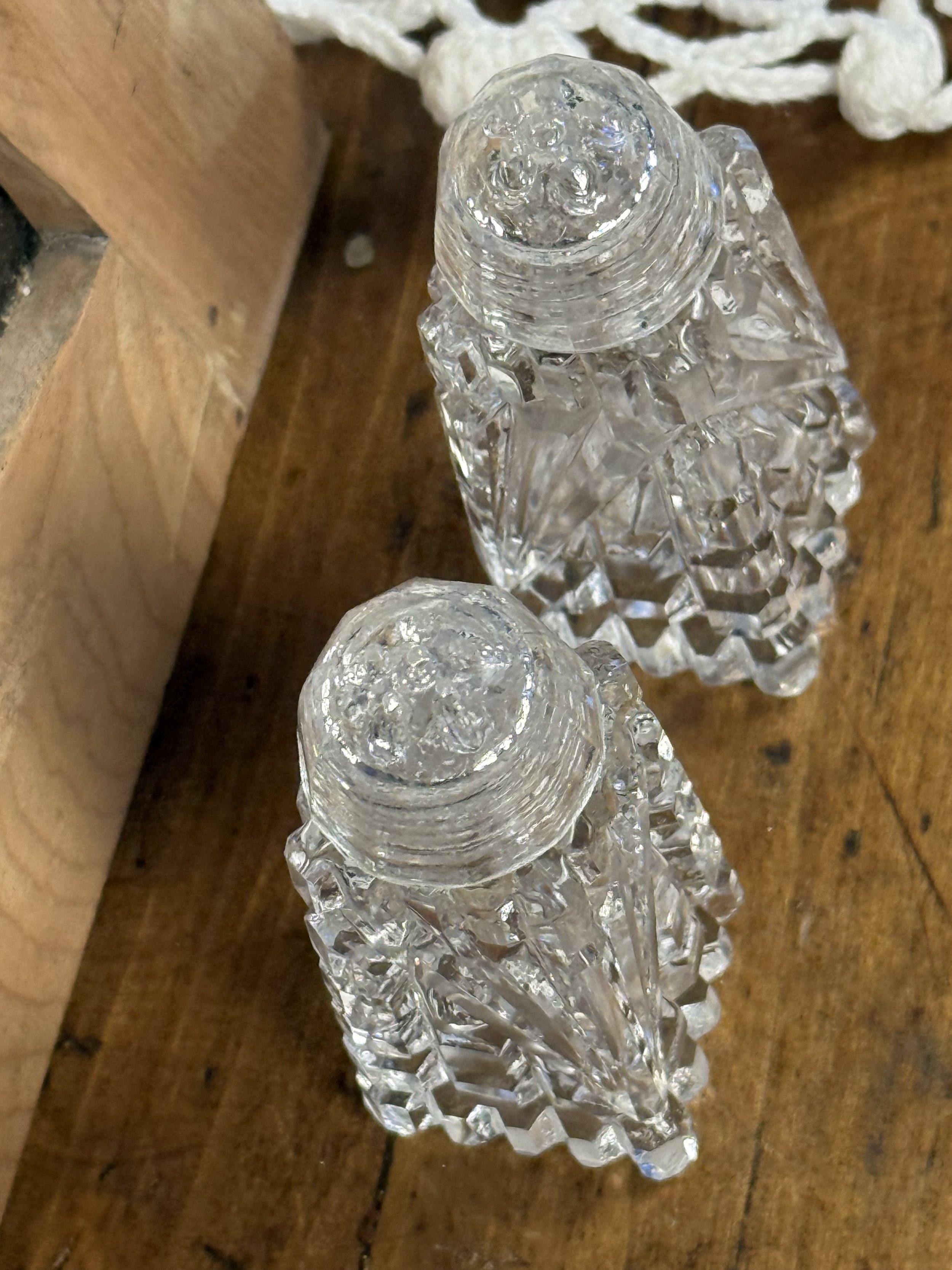 Disassembled vintage glass salt and pepper shakers showing threaded glass lid and interior opening, clear cut glass construction, functional retro kitchenware