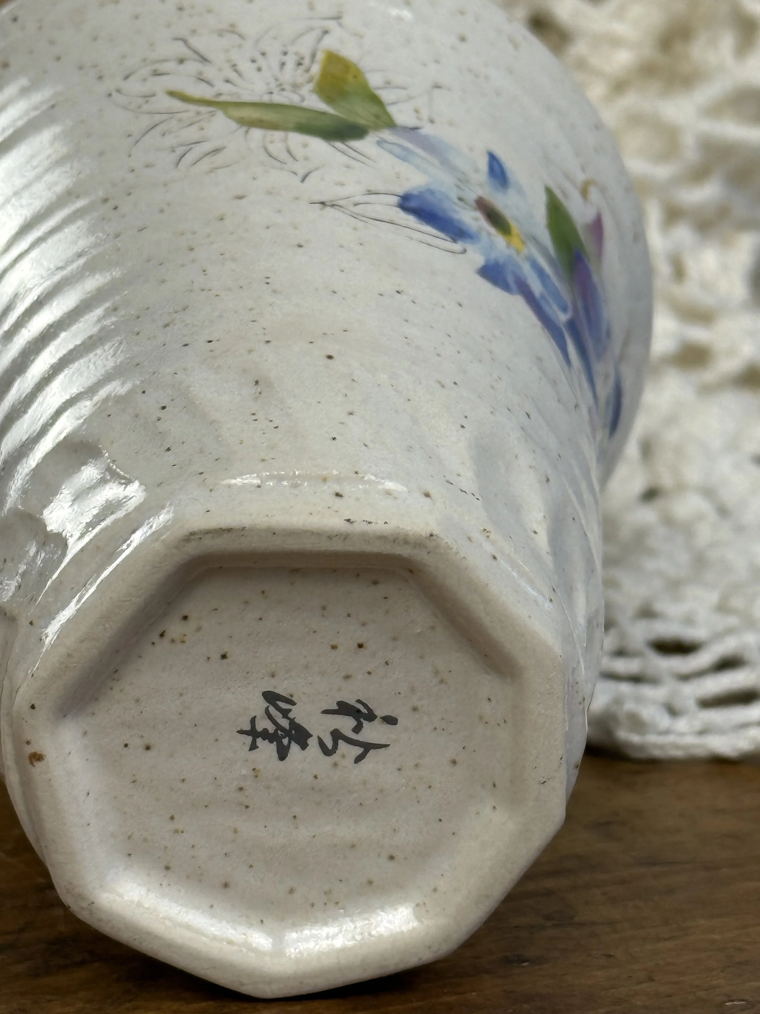 Base view of Japanese stoneware vase showing octagonal foot and artist mark, speckled clay body with hand-painted floral decoration visible above
