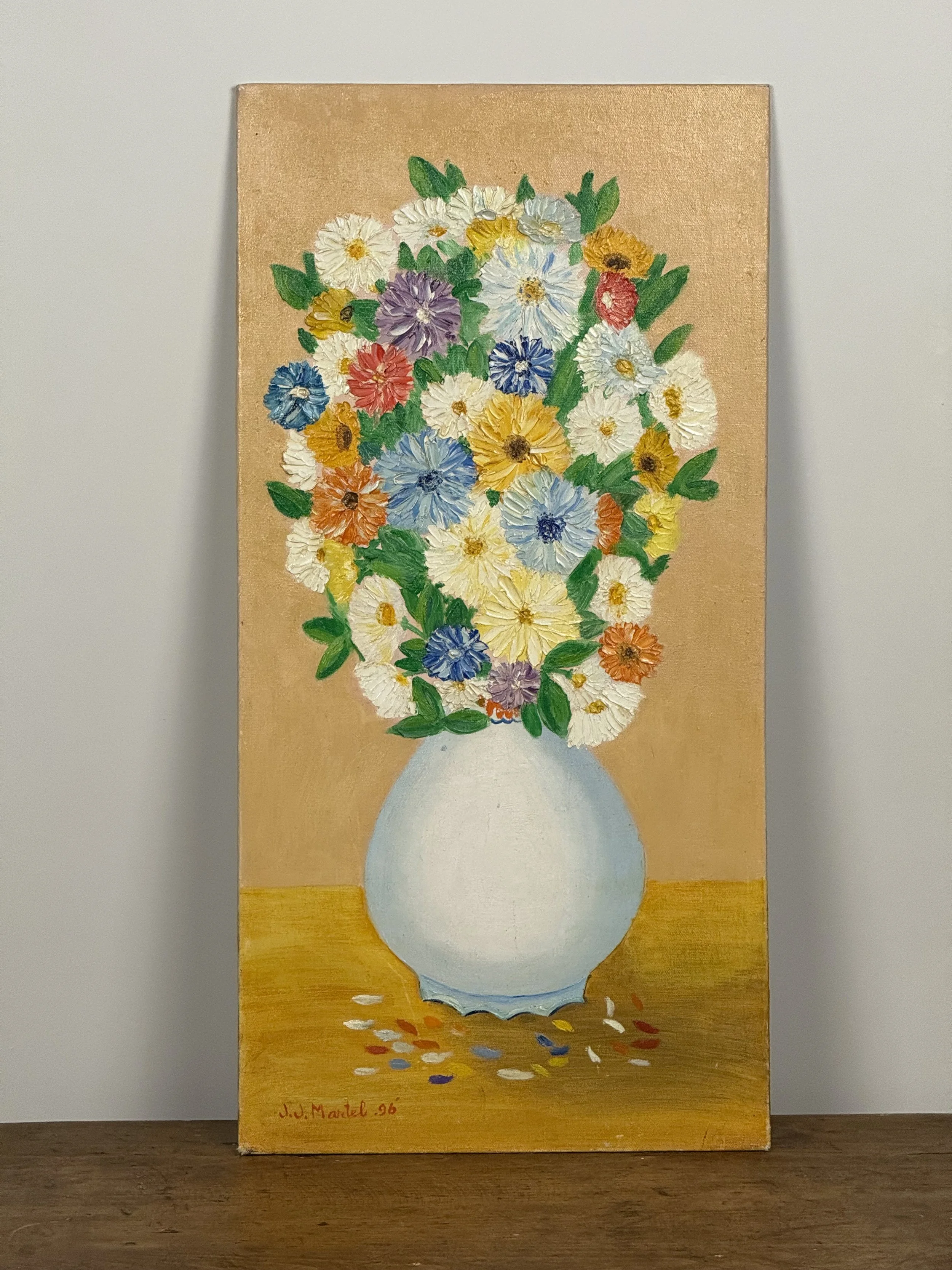 Vintage 1996 naïve folk art oil painting by J.J. Martel showing a pale vase of textured impasto flowers in bright multicolor tones on a warm ochre table