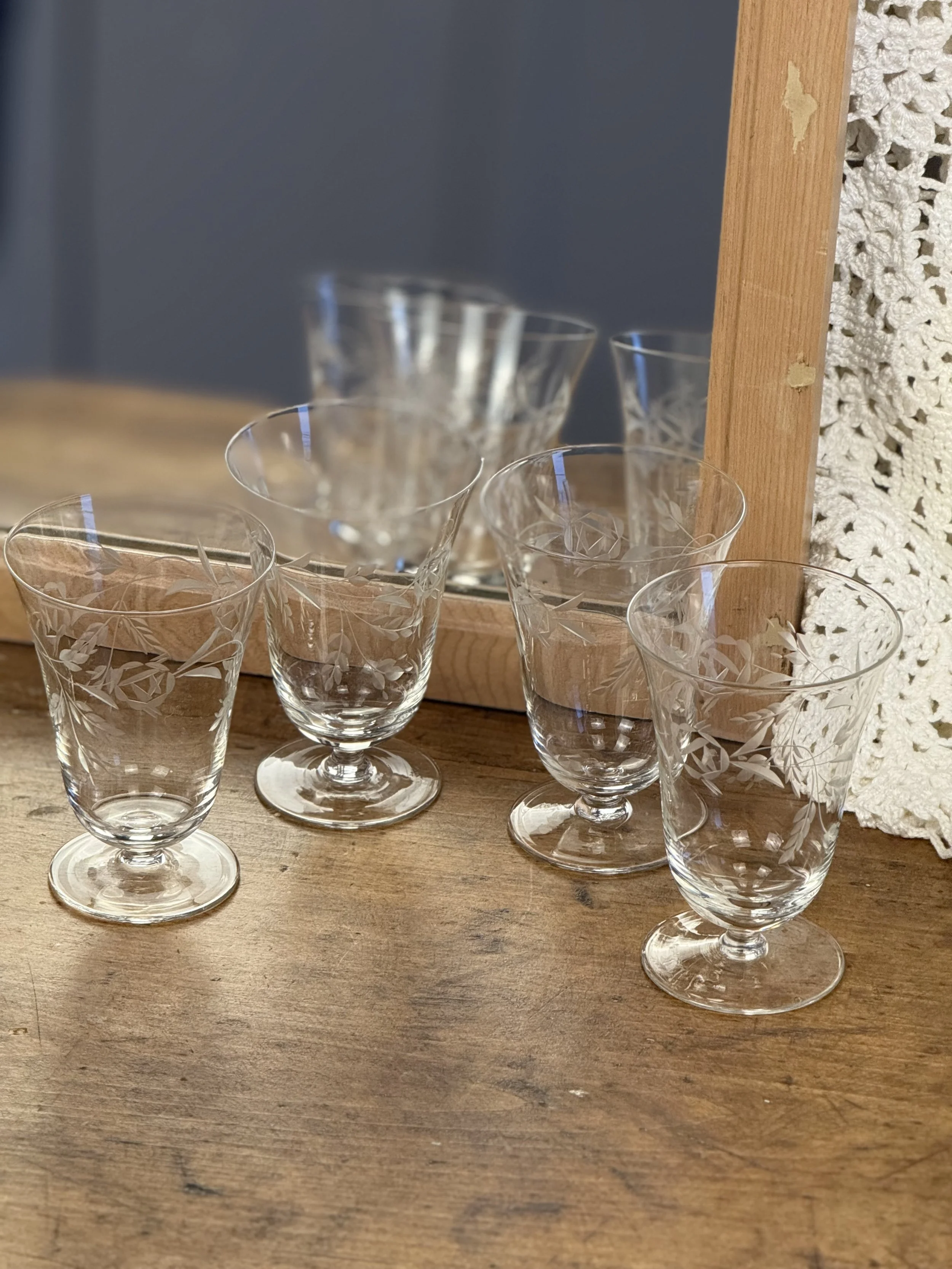 Set of four vintage etched cocktail glasses reflected in mirror, clear floral-engraved glass with short stems, elegant classic entertaining glassware