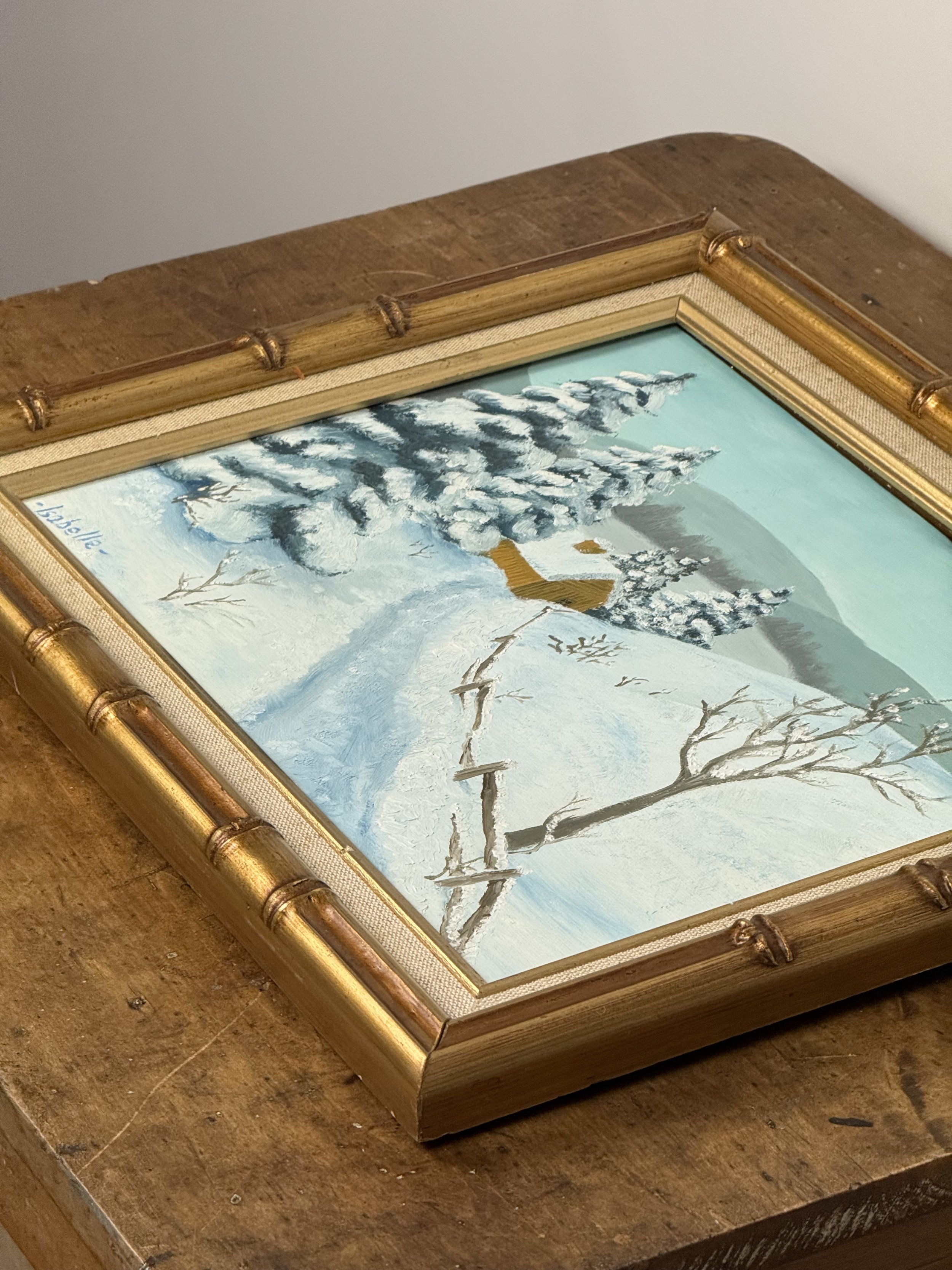 Angled view of gold bamboo-style frame and painted winter scene, framed vintage landscape artwork