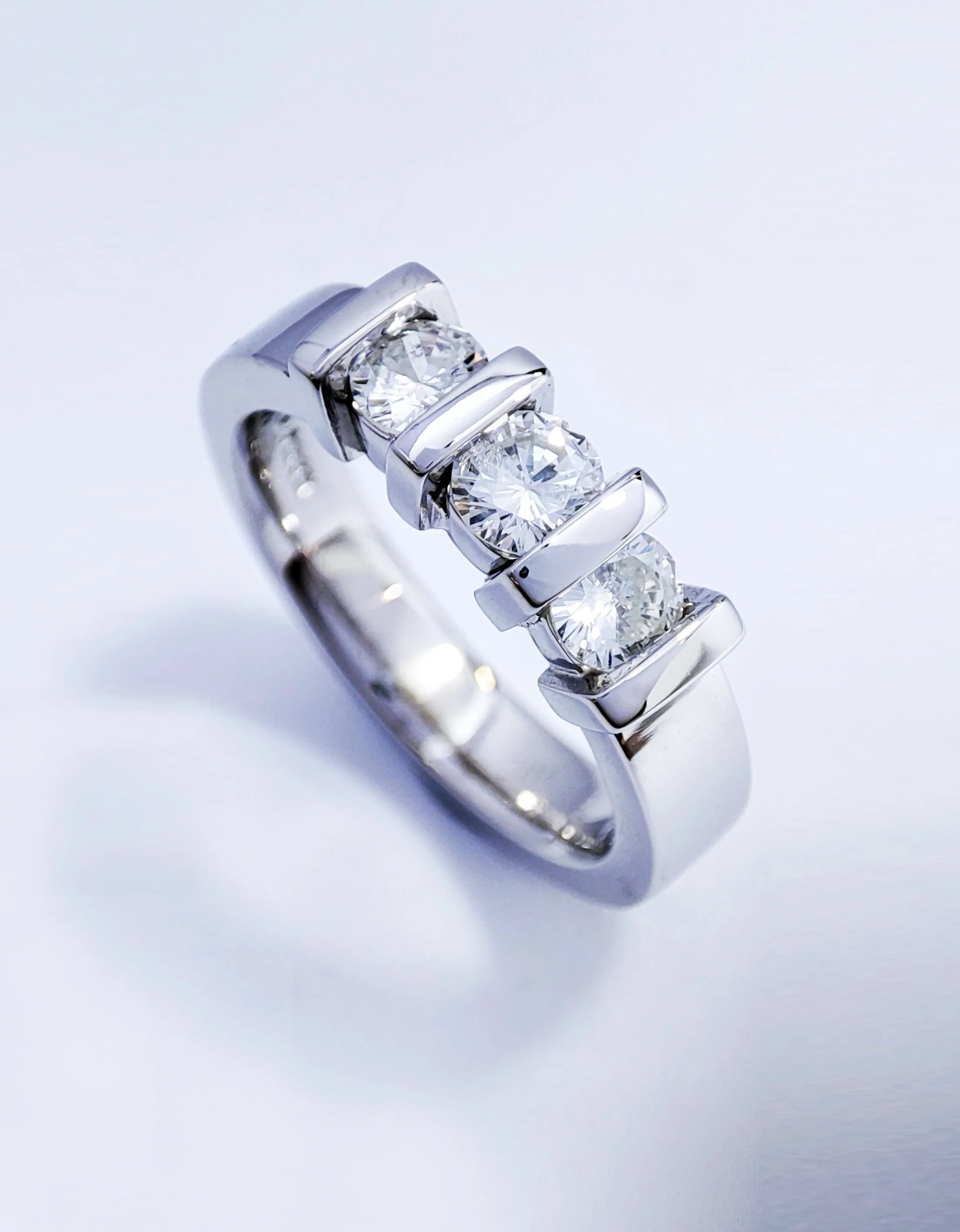 A silver ring with four prominent round-cut diamonds set in a row.