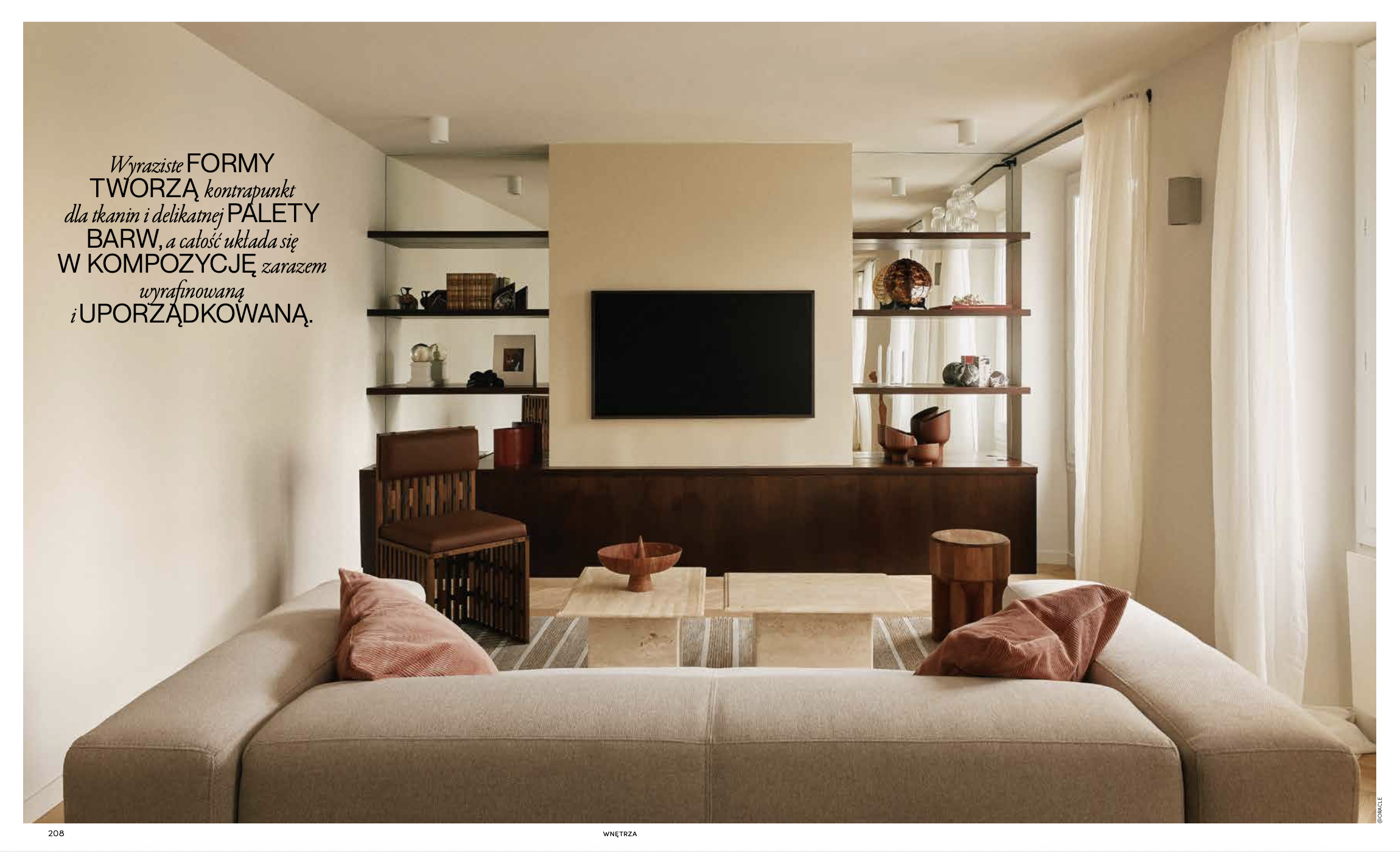 Salon avec canapé beige, coussins roses, table en pierre, étagères en bois avec décorations, téléviseur à mur, rideaux blancs, meubles en bois.