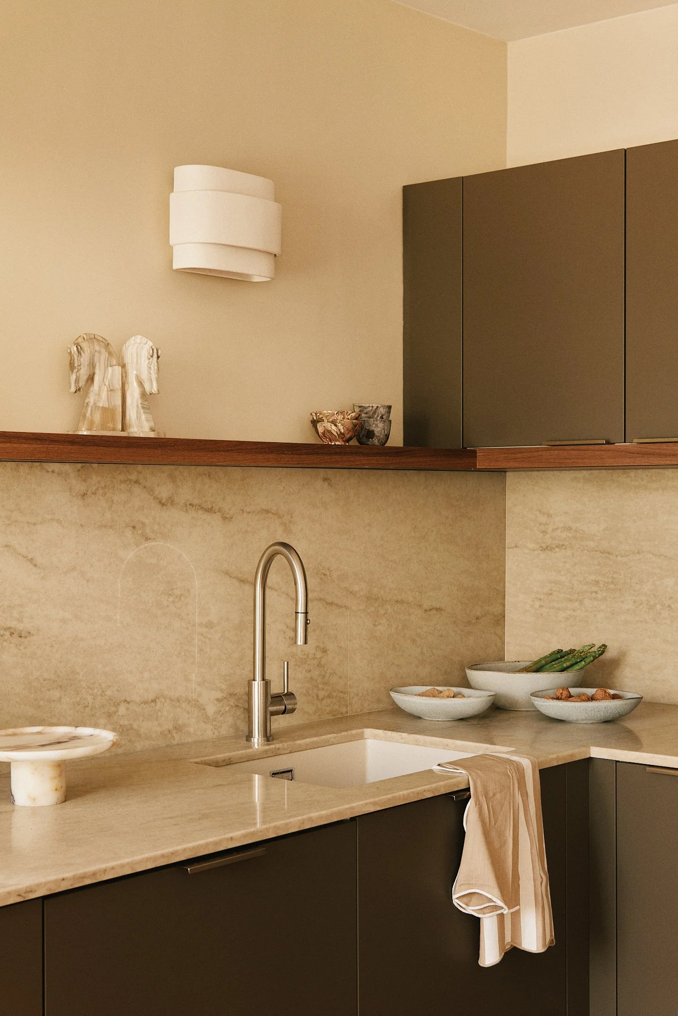 Cuisine moderne avec un évier, des bowls contenant extrapices, et des décorations d'anges en céramique sur la étagère.